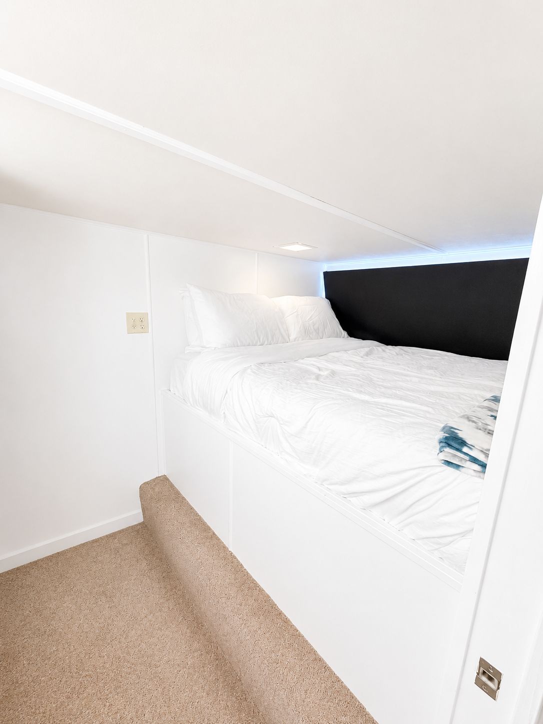 A cozy bedroom with a large bed and white bedding on a houseboat.