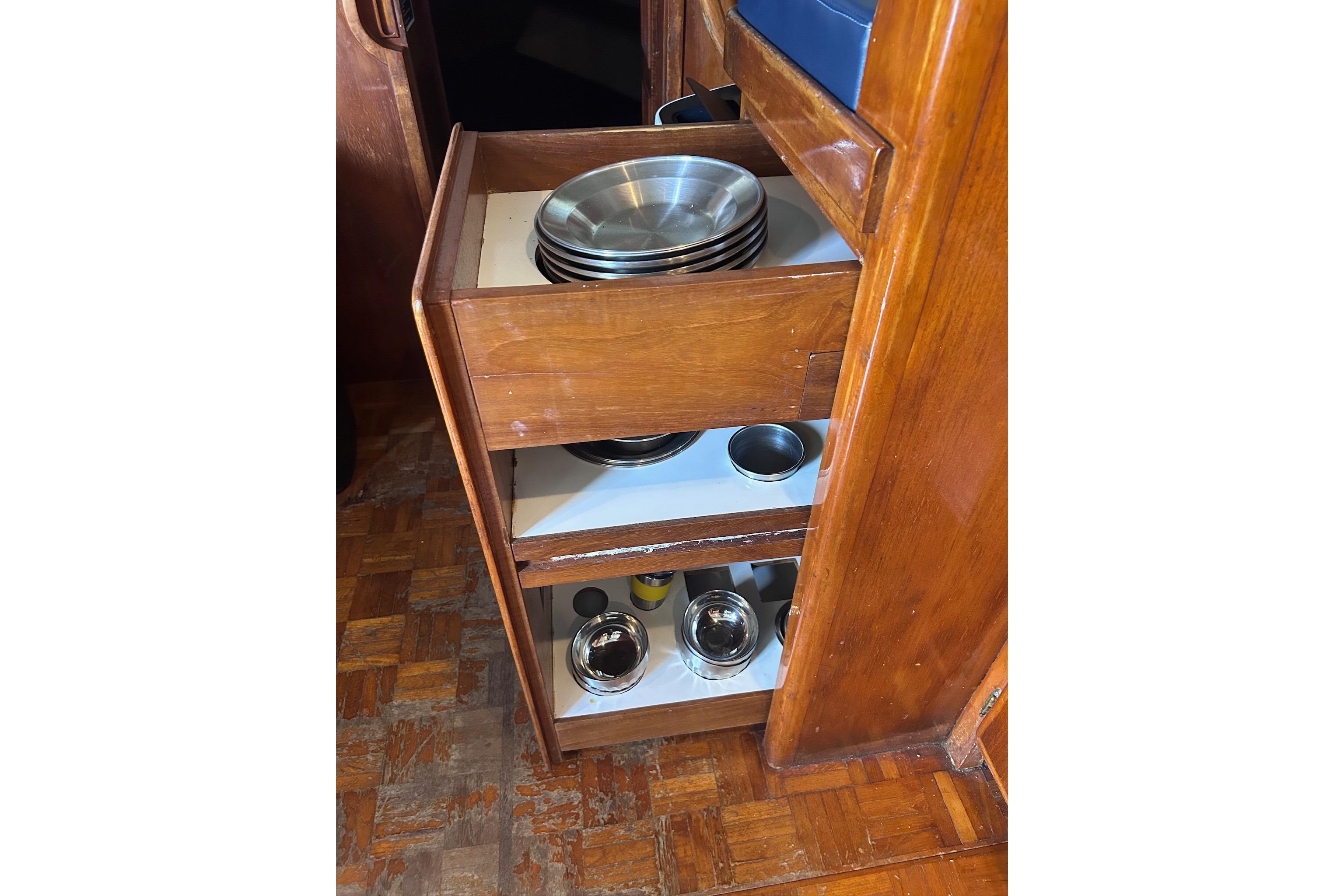 Wooden cabinet with metal dishes in a 1977 Marine Trader 40 Double Cabin boat.