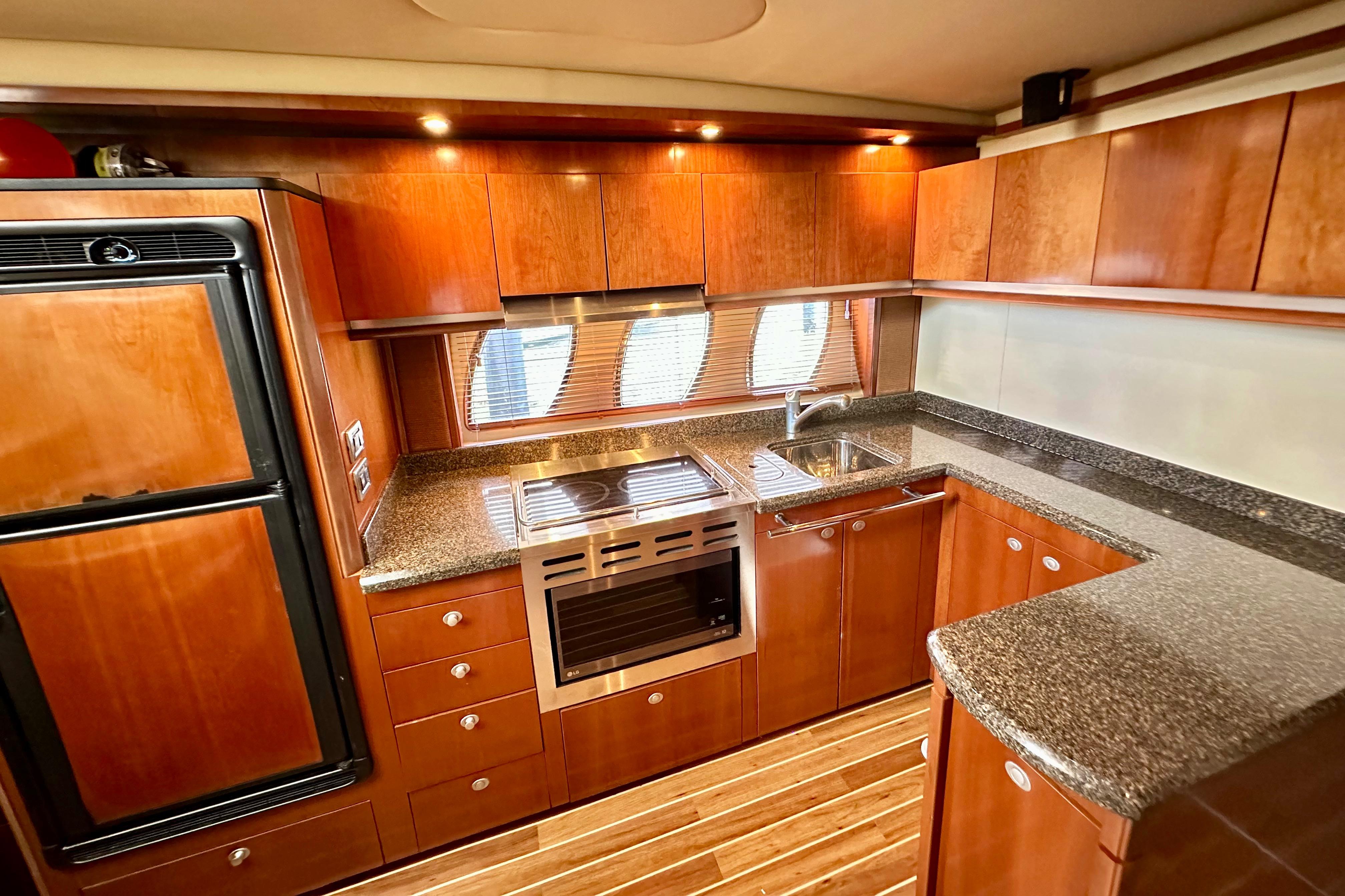 Luxurious kitchen interior of 2005 Sea Ray 48 Sundancer yacht with wood cabinetry and modern appliances.