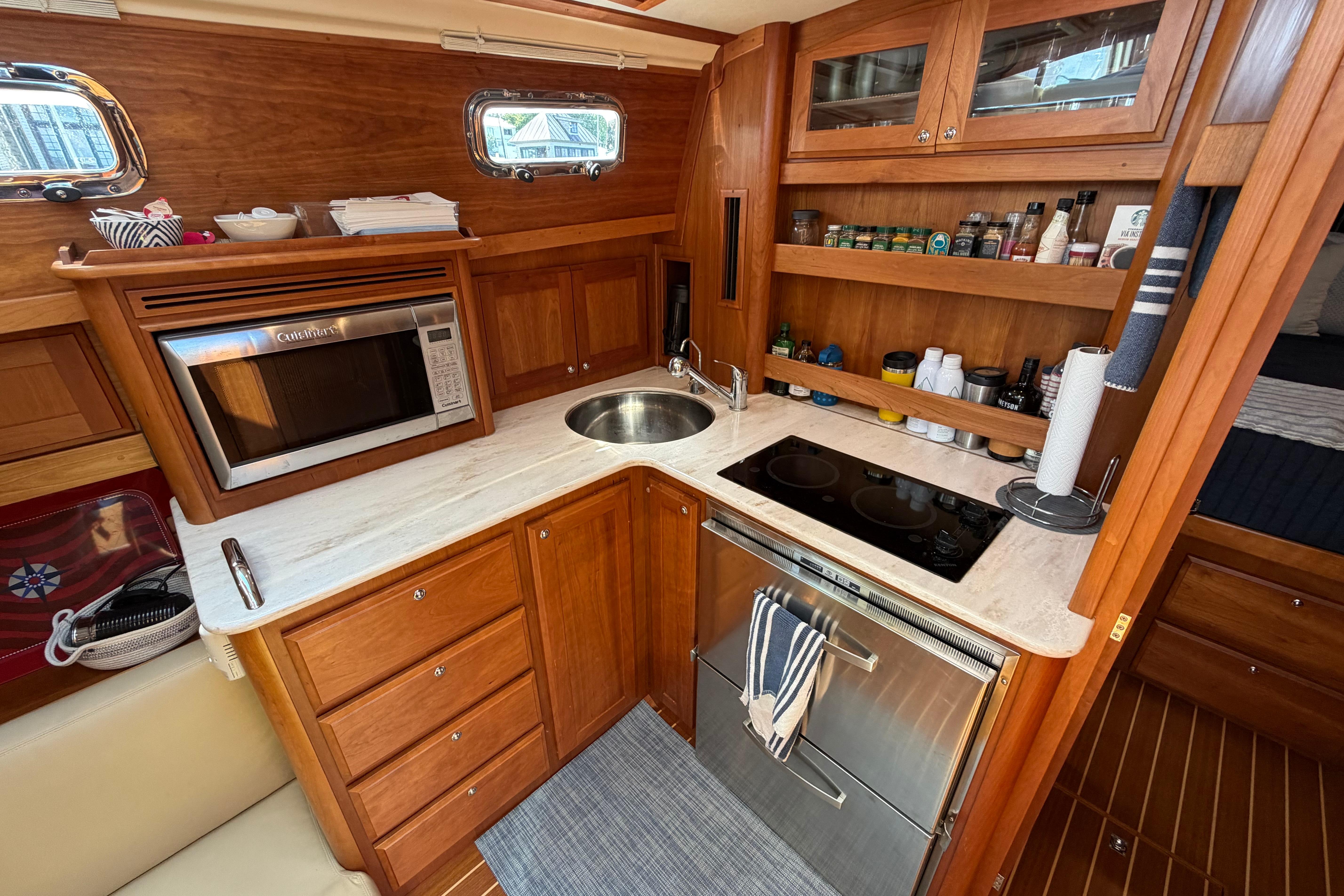2015 Sabre 38 Salon Express yacht kitchen with wood cabinetry, microwave, stove, and sink.