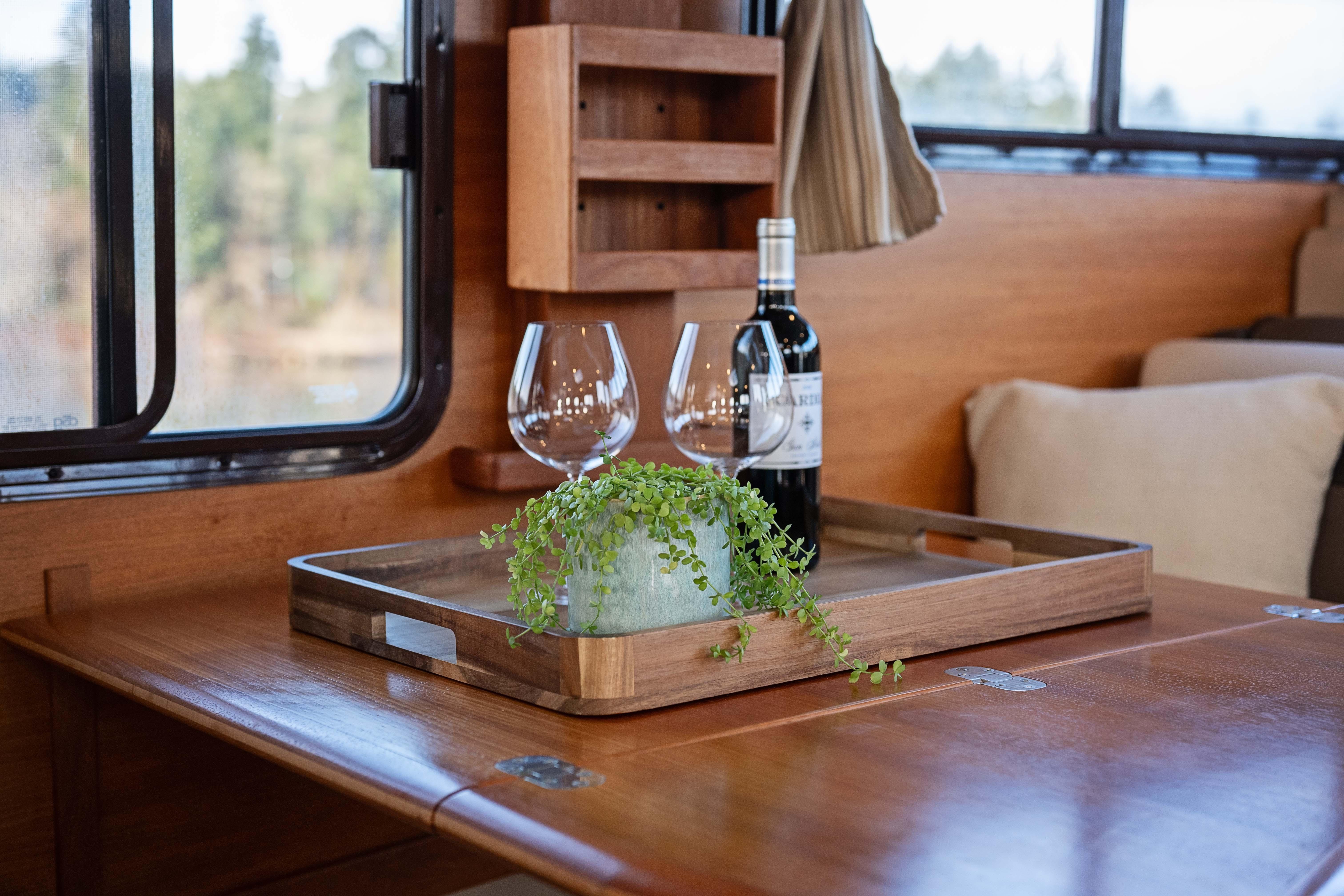 Interior of 2014 Ranger Tug R-31 CB with wine, glasses, and plant on wooden table.