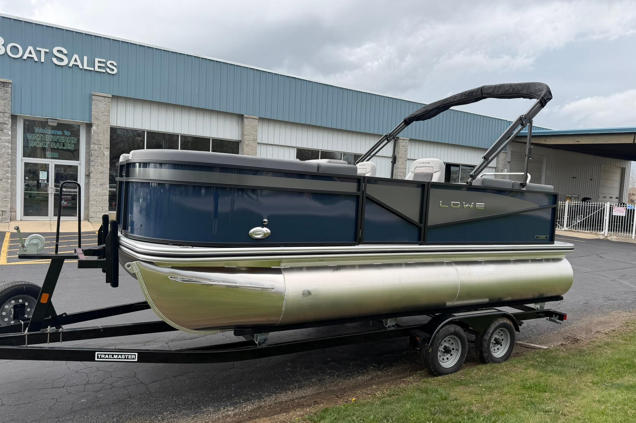 2026 Lowe LS 190 pontoon boat on trailer outside dealership.