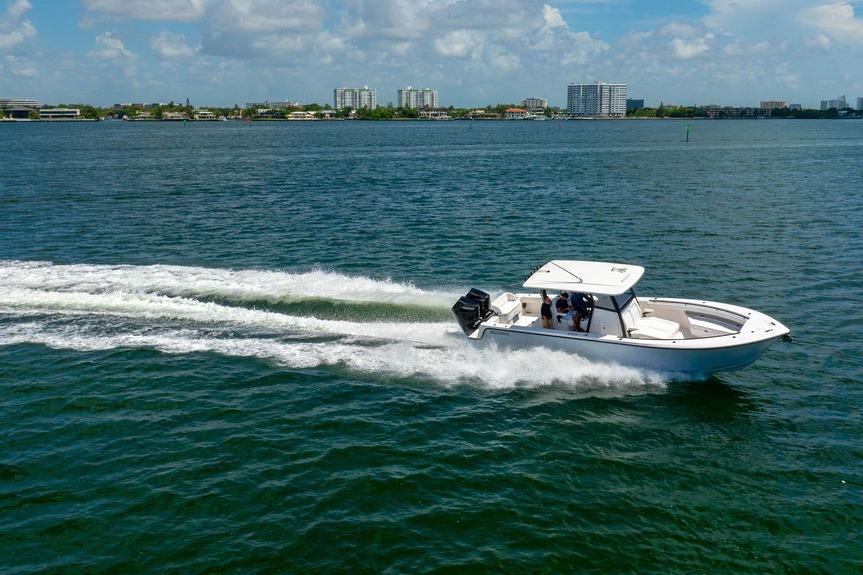 2027 Reef Runner 340 boat cruising on a sunny day, with city skyline in the background.