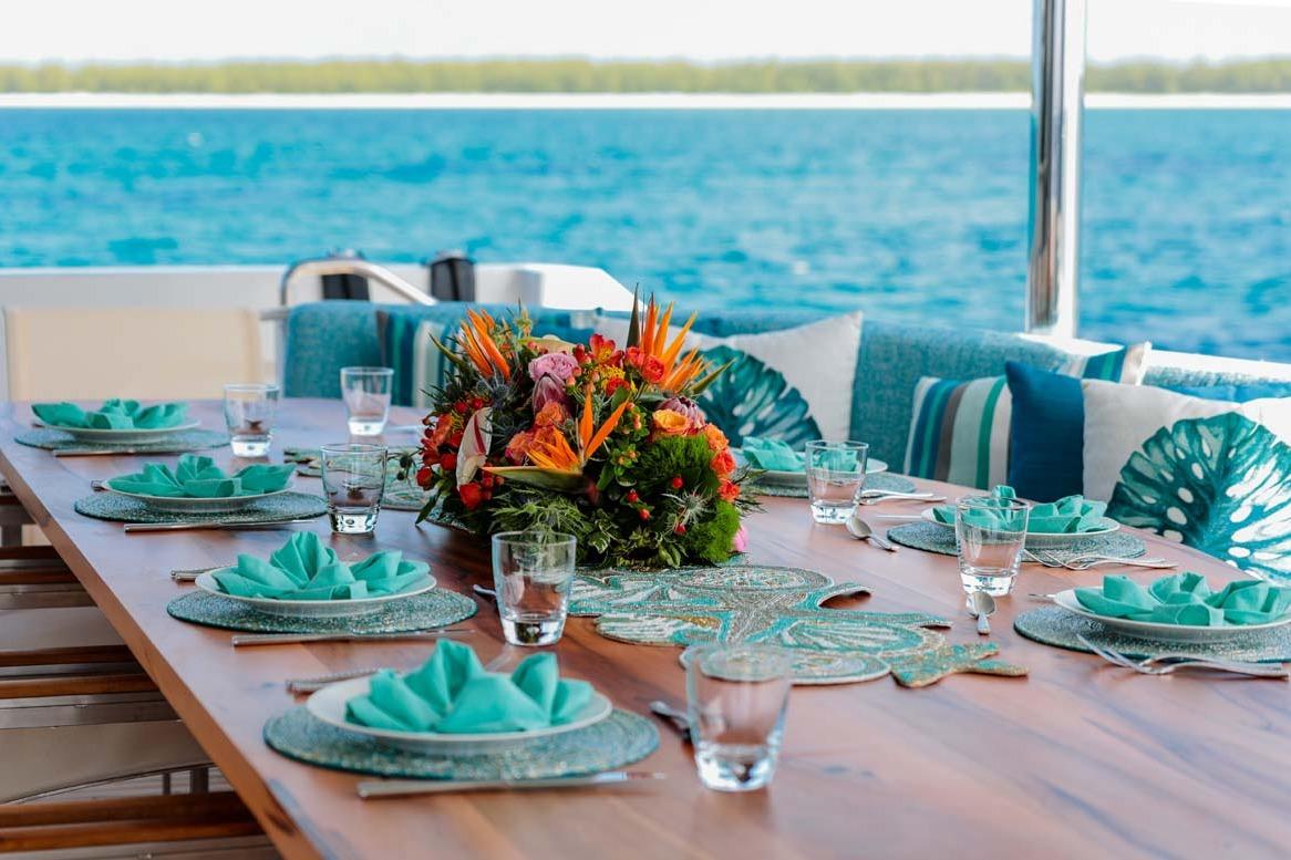 Elegant dining setup on 2001 Westship Skylounge yacht with ocean view and floral centerpiece.