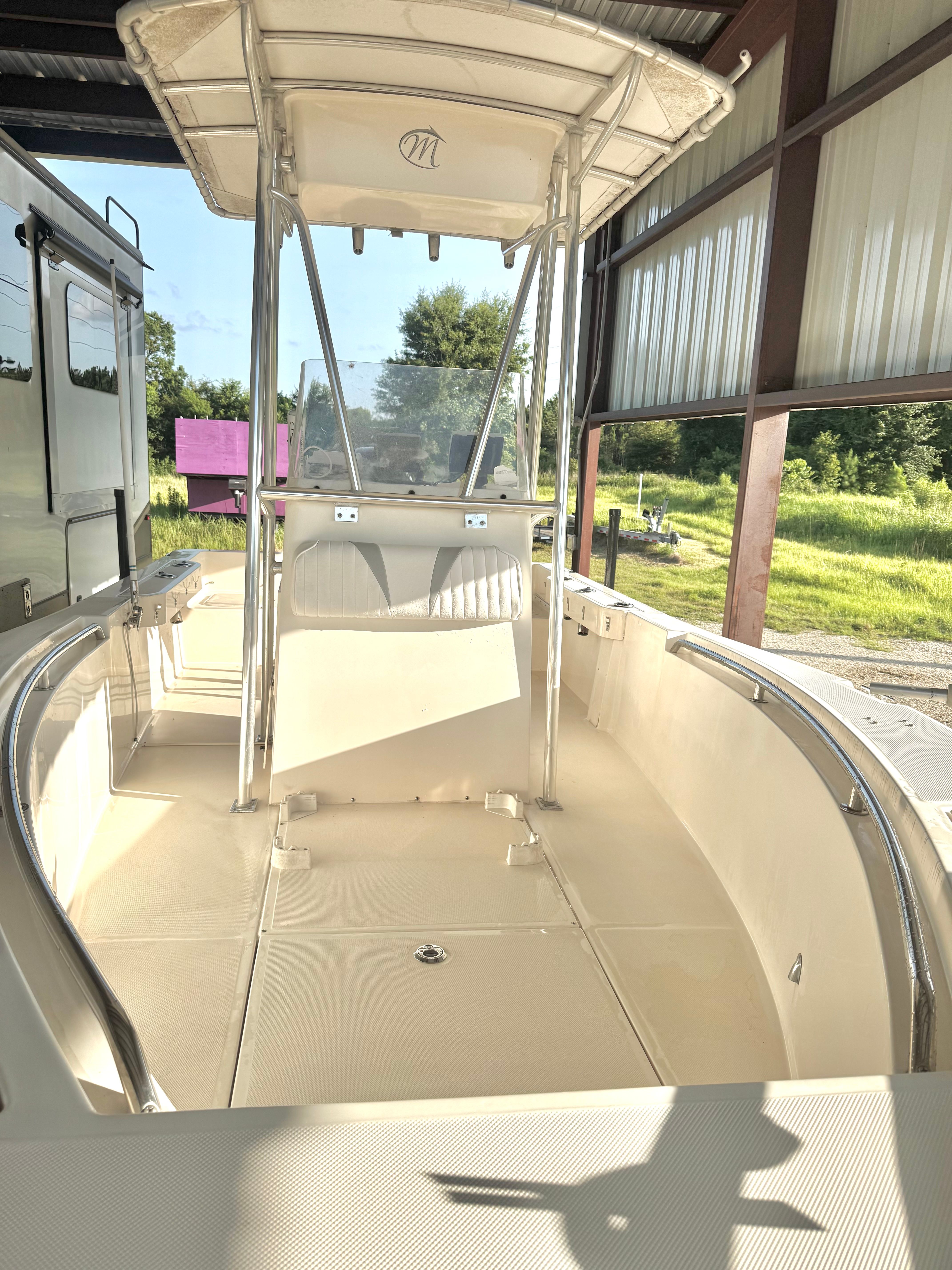 A 2007 McKee Craft Marathon 196 CC boat in a covered area. It features a T-top and open deck space.