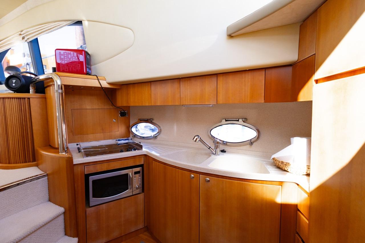 Luxurious kitchen interior of 2005 Azimut 46 yacht with modern amenities and wooden cabinetry.