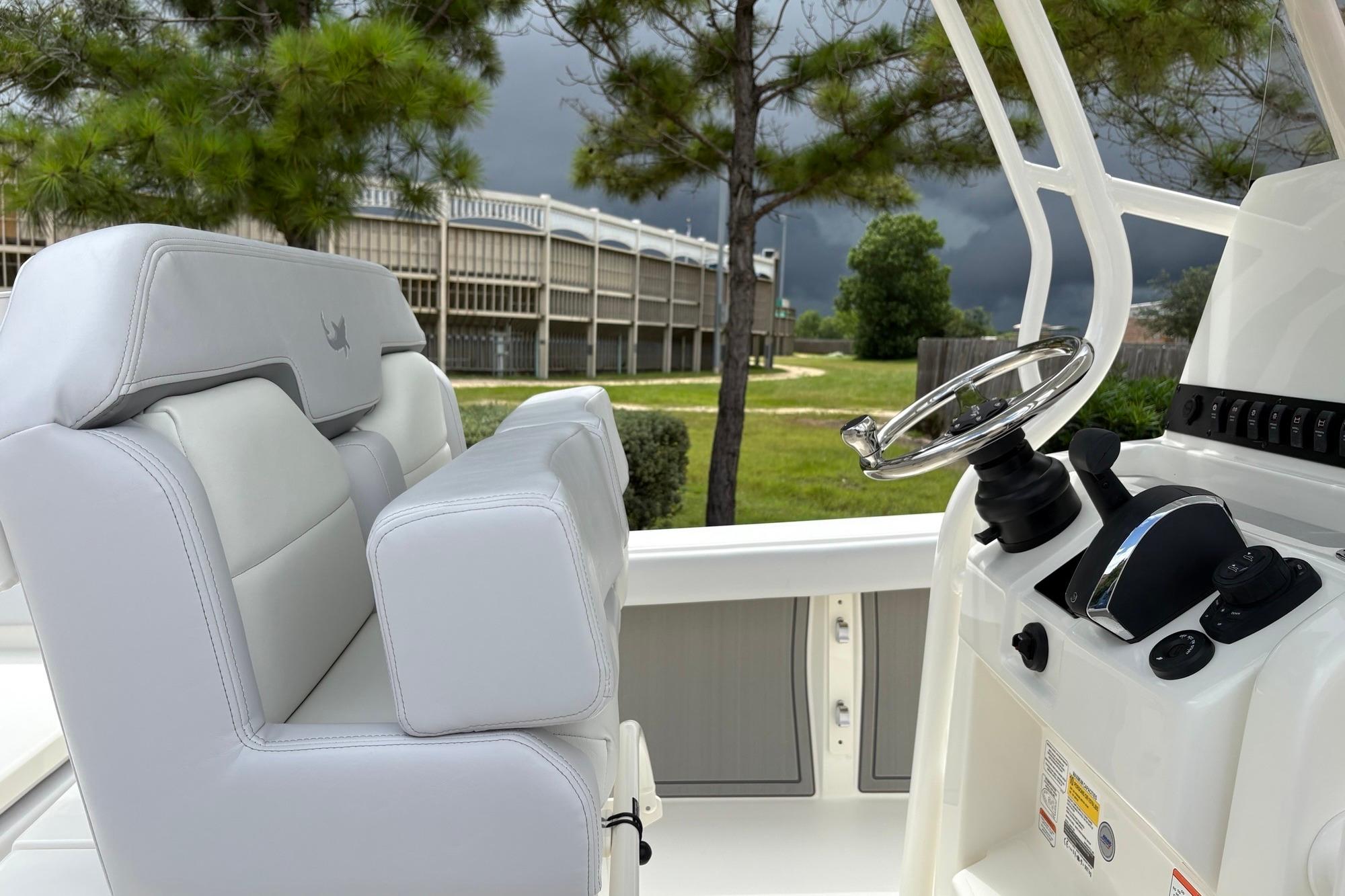 2026 Mako 226 Center Console boat interior with steering wheel and seating, under cloudy sky.