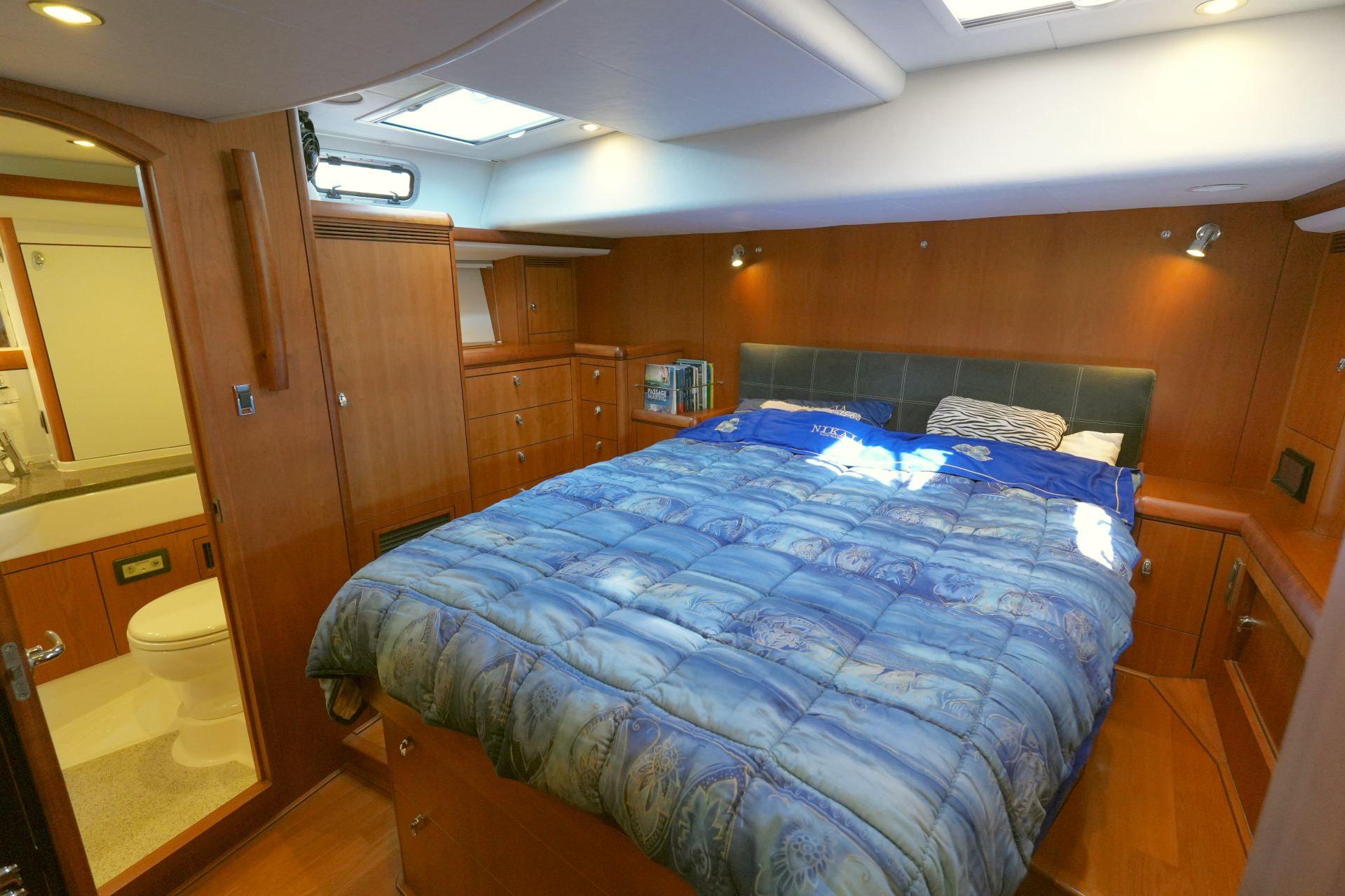 Luxurious bedroom in 2011 Oyster 575 yacht with wood paneling and ensuite bathroom.