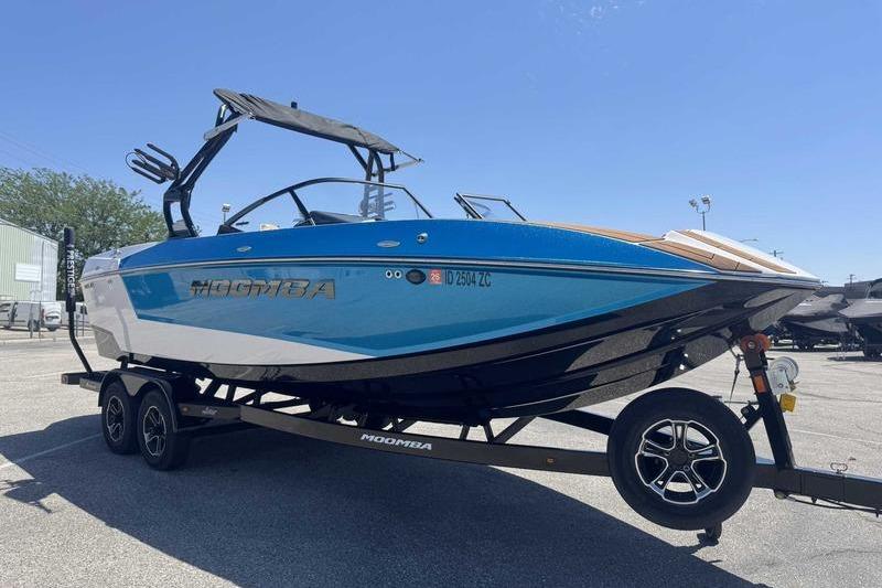 2023 Moomba Mojo Pro boat on trailer, blue and white design, parked outdoors.