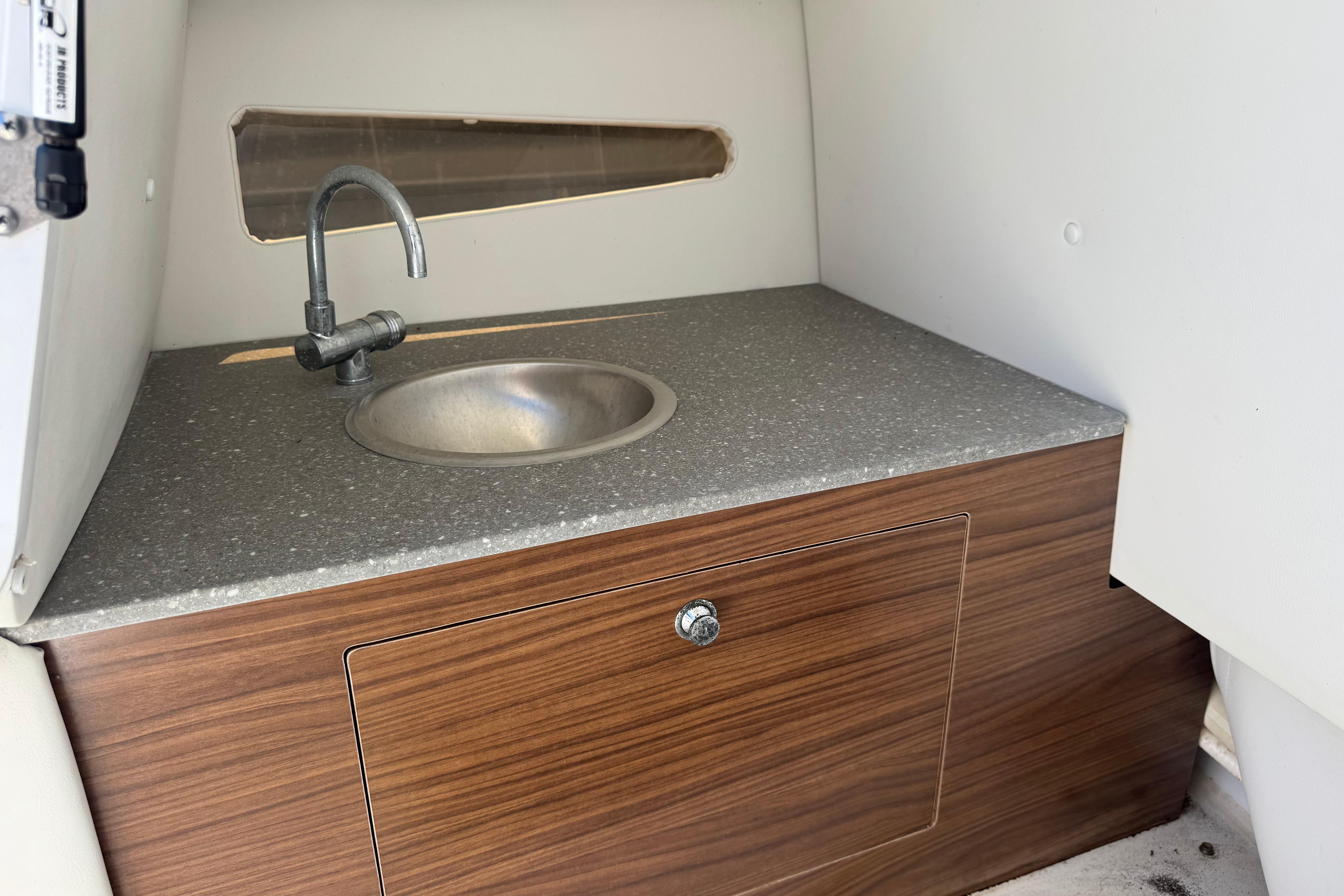 2020 Glastron GTD 240 boat interior with compact sink and wooden cabinet.