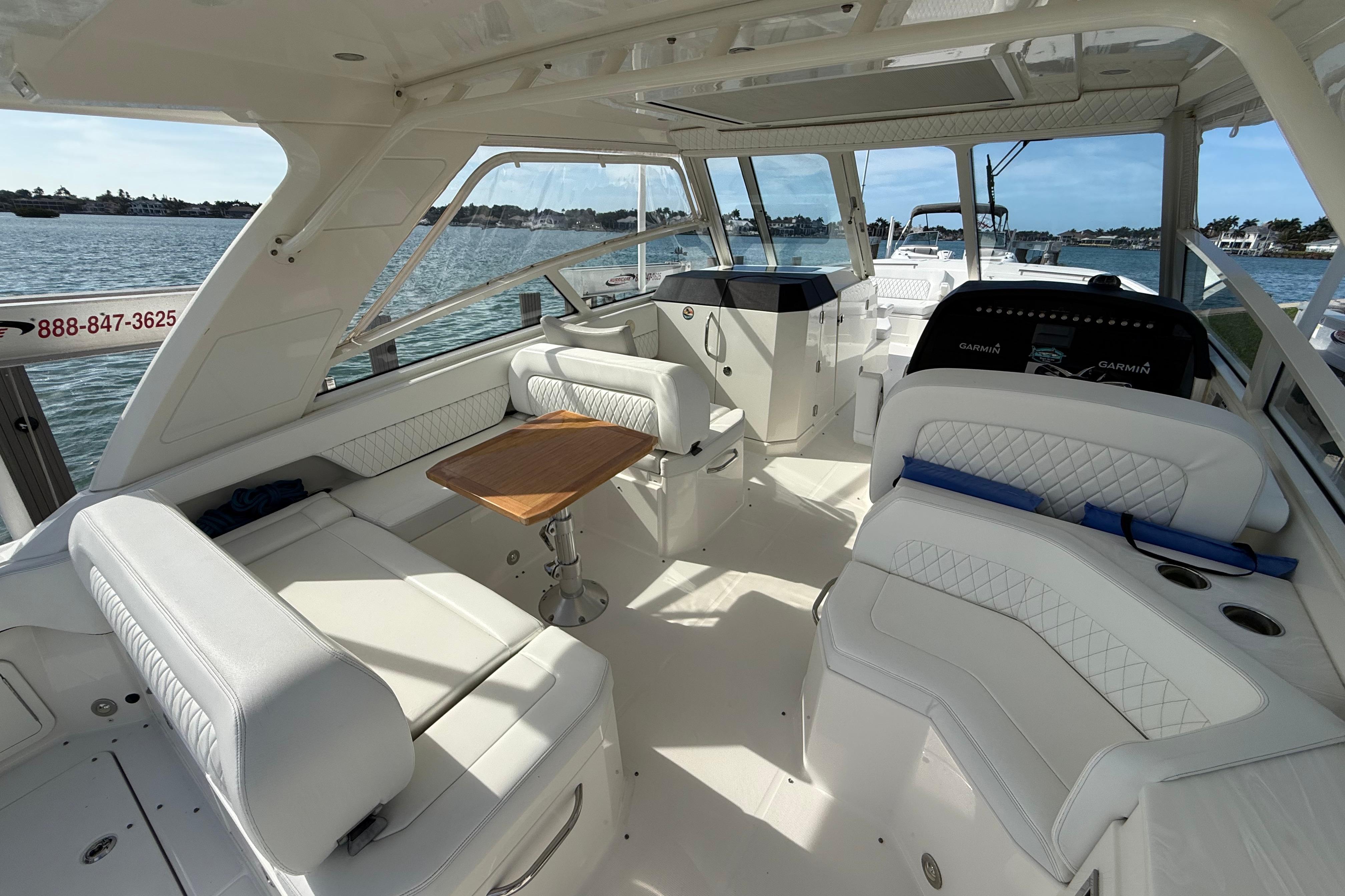 Luxurious 2021 World Cat 400 DC-X boat interior with white seating and wooden table.