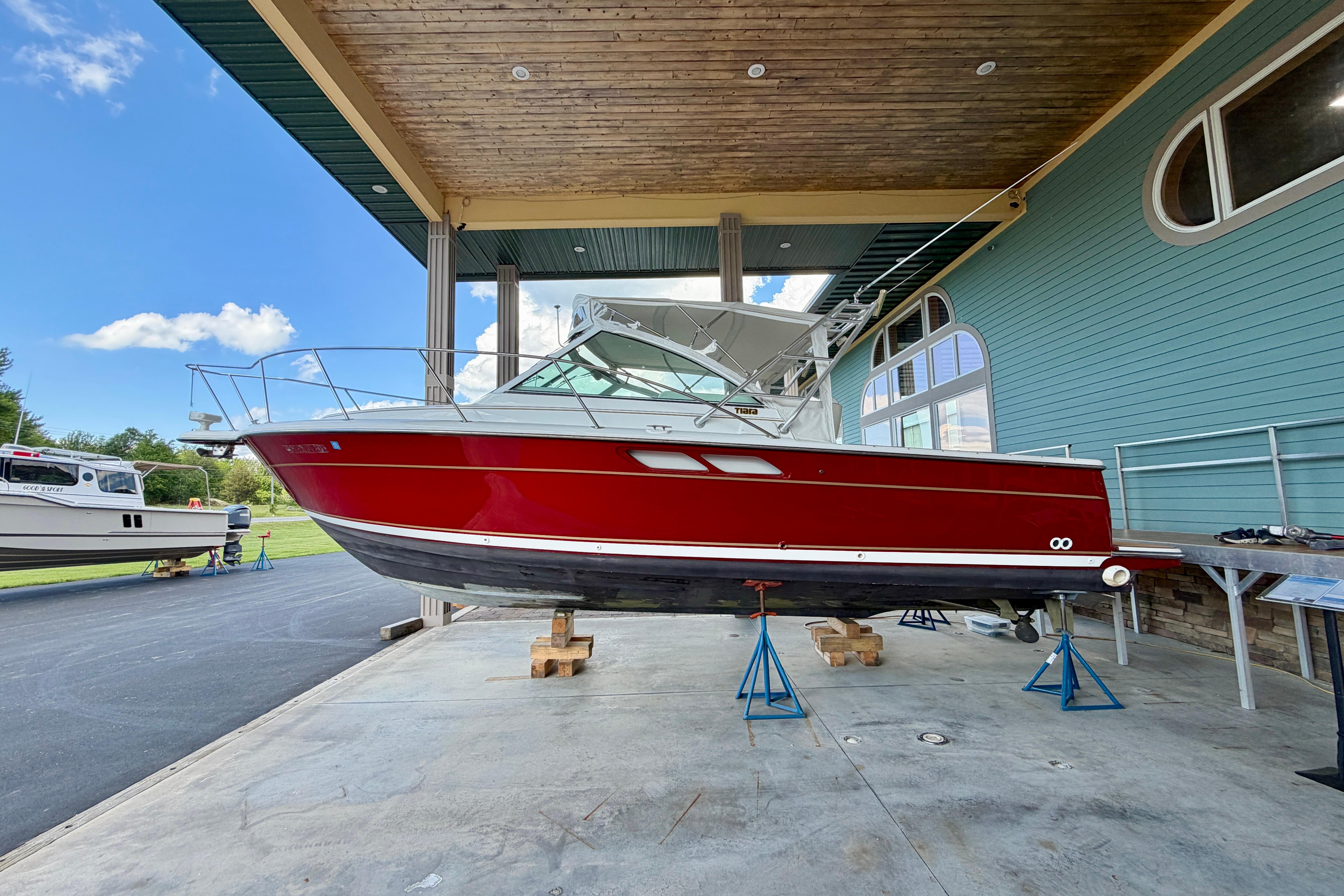 1999 Tiara Yachts 2900 Coronet in red, displayed on stands under a covered area.