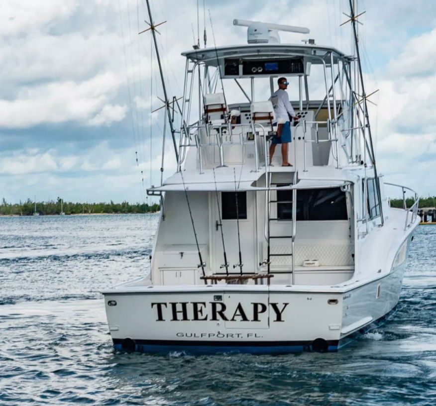 A 1979 Hatteras sport fishing boat on the water with a man on the deck.