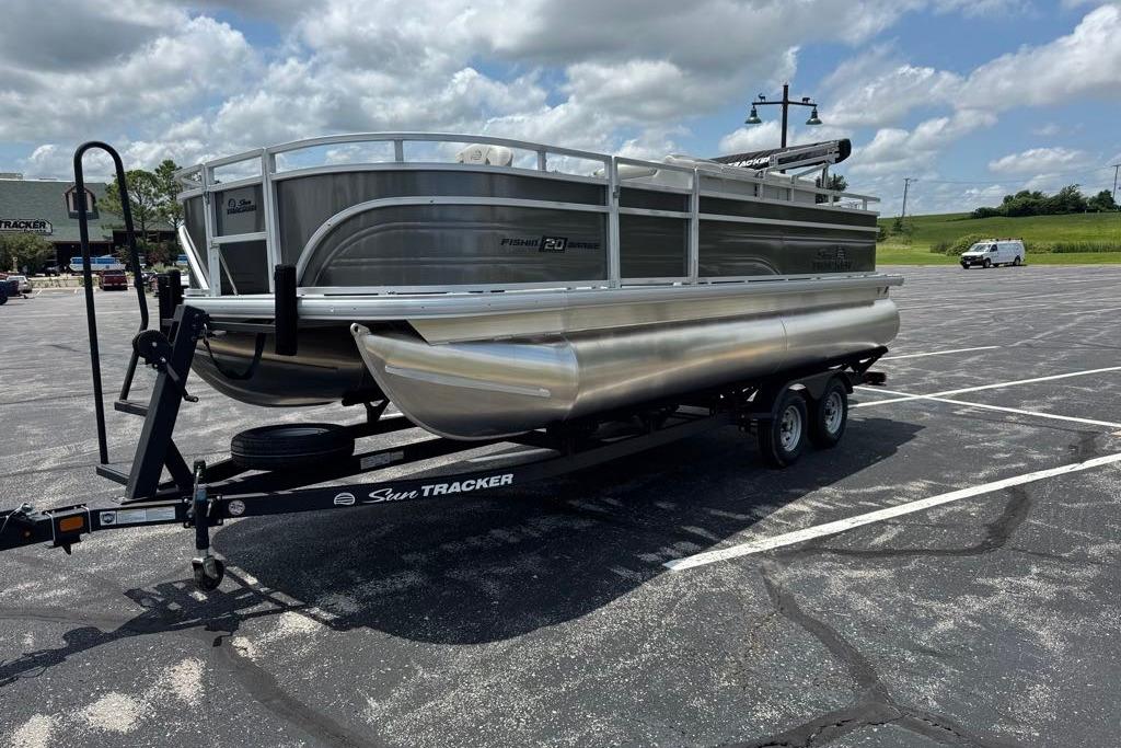 2026 Sun Tracker Fishin' Barge 20 DLX pontoon boat on trailer in parking lot.