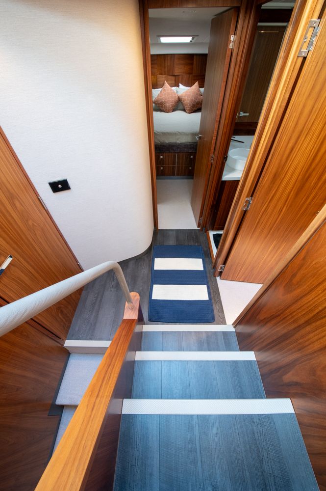 Interior of 2022 Riviera 6000 Sport Yacht Platinum, featuring wooden stairs and cozy bedroom.