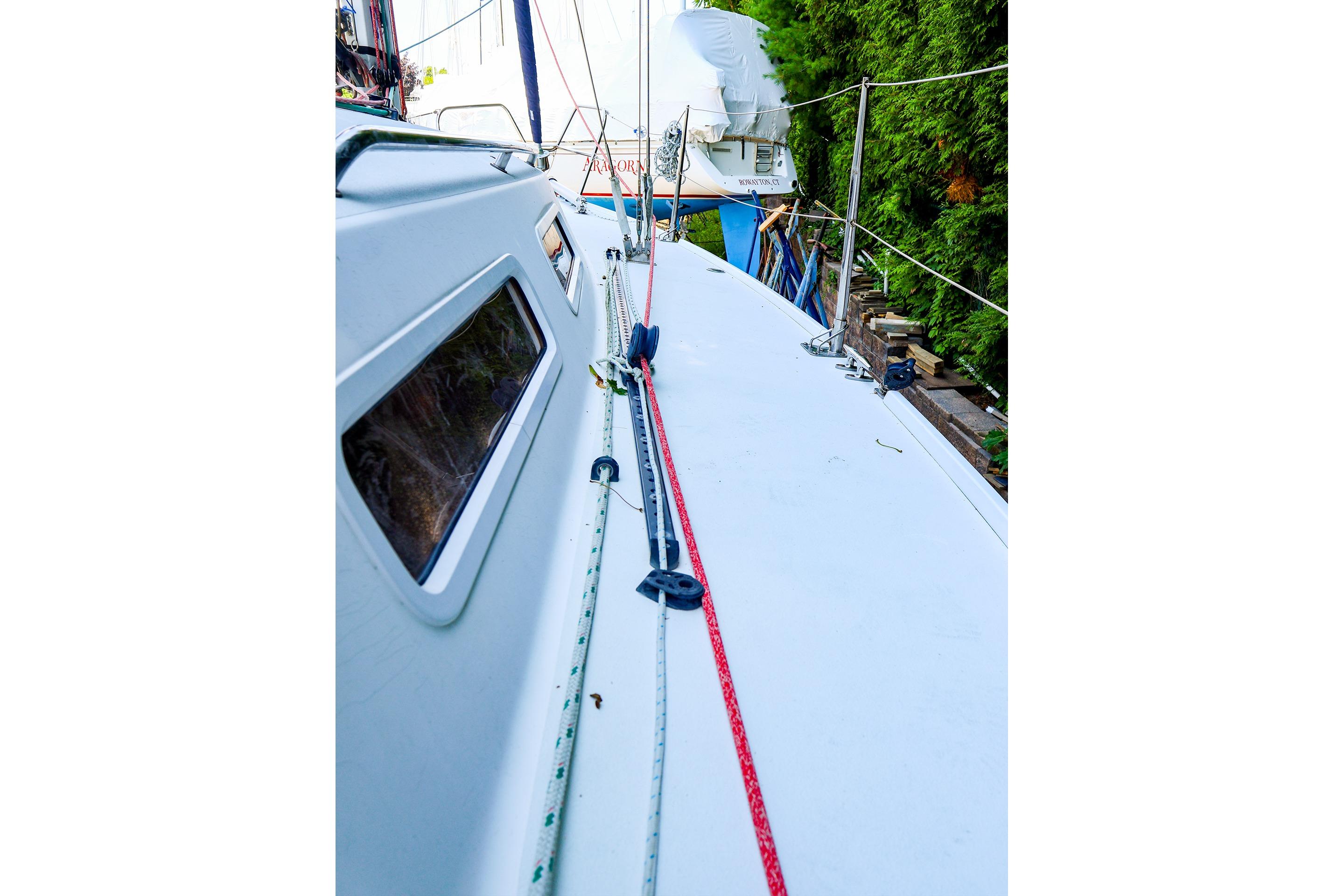 2001 J Boats J/32 sailboat deck with rigging and lush greenery background.