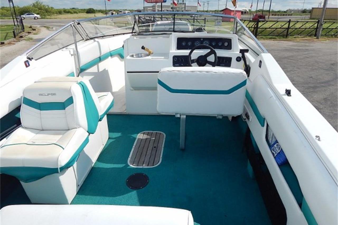 1991 Wellcraft Eclipse 232 boat interior with teal and white seating, steering wheel, and dashboard.