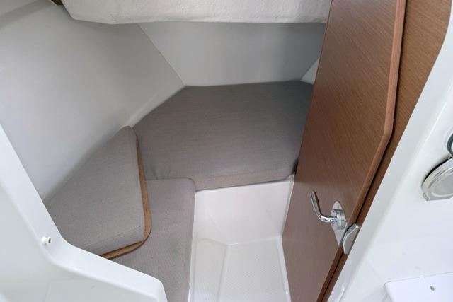 2018 Jeanneau NC Sport 695 cabin interior with cozy gray bedding and wooden door.