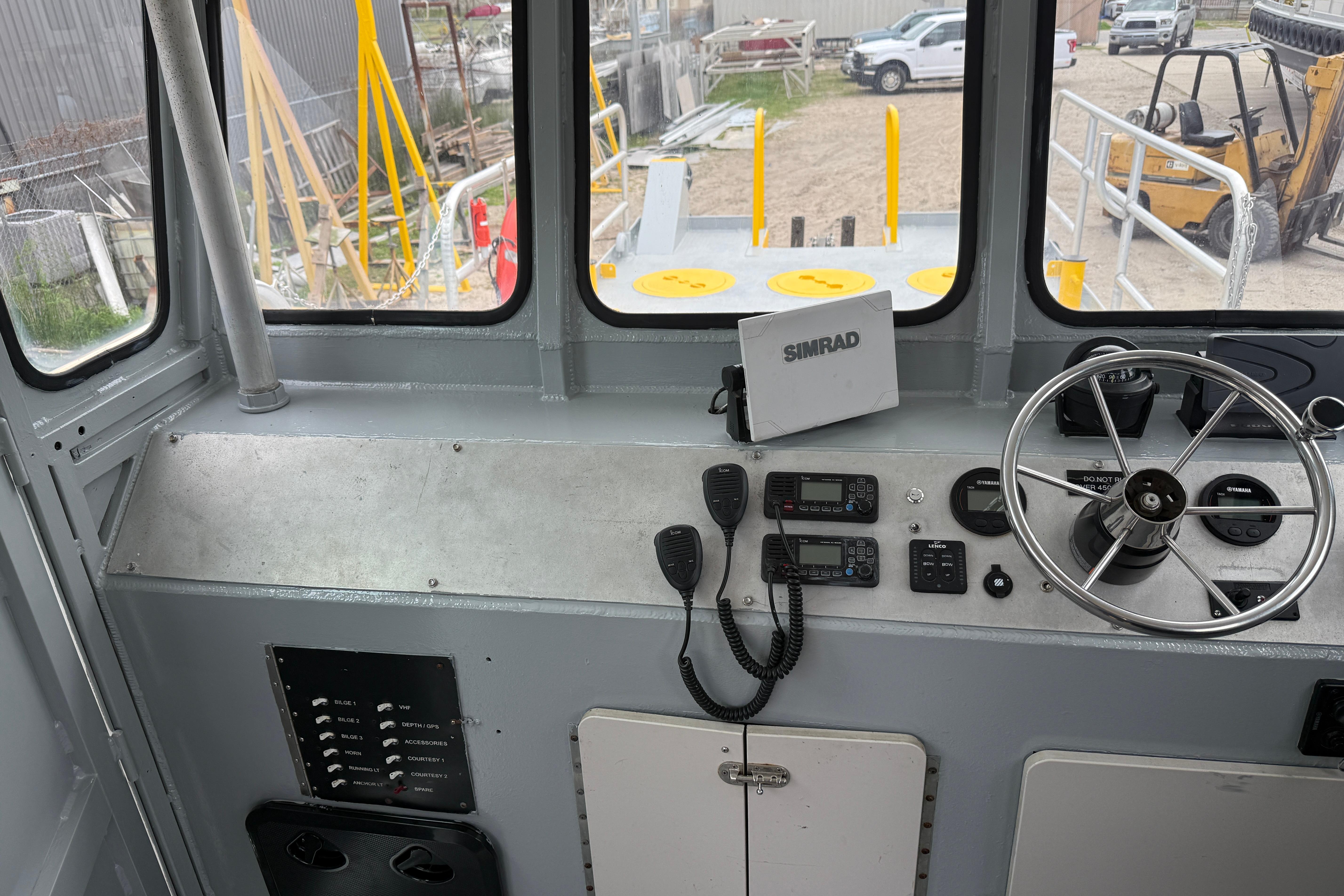 Pilothouse interior of 2010 Custom Aluminum Work Boat, featuring steering wheel and navigation equipment.