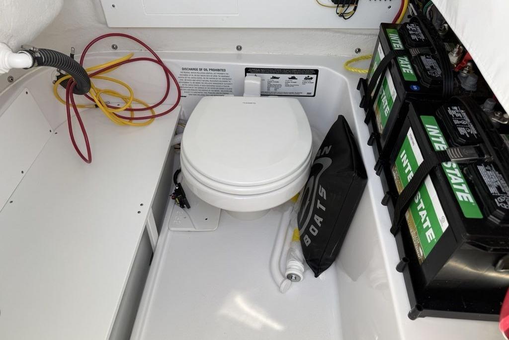 2026 Sportsman Open 232 Center Console boat interior with toilet and batteries.