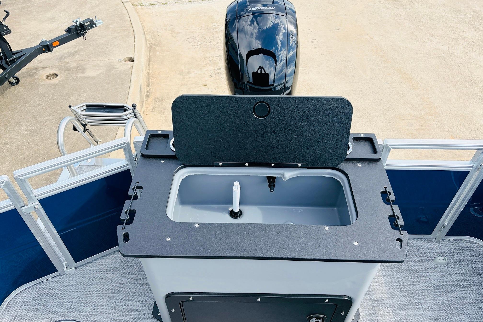 2026 Sun Tracker SportFish 22 DLX boat with open livewell and Mercury outboard motor.