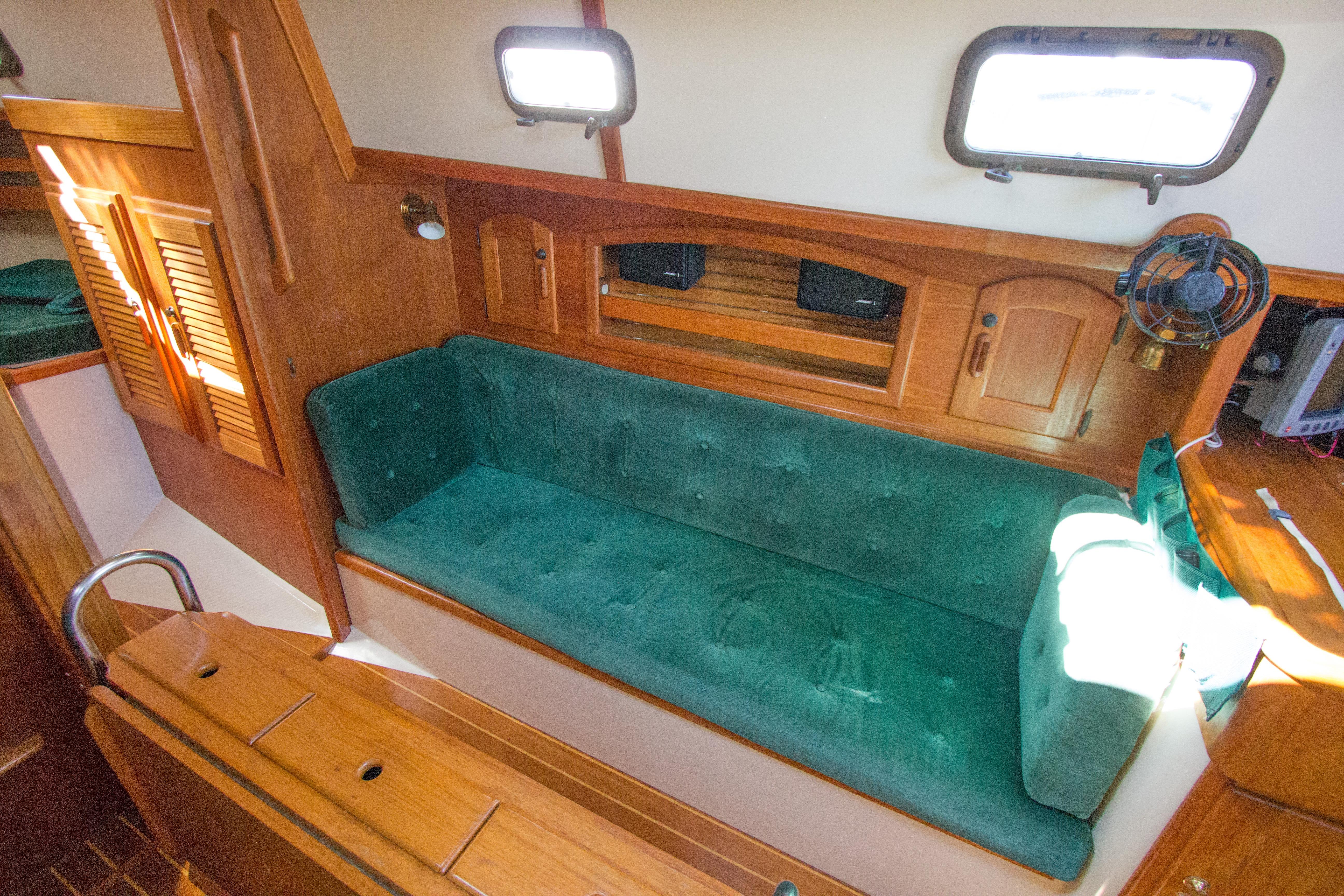 Interior of 1992 Pacific Seacraft 34 sailboat with green cushioned seating and wooden cabinetry.