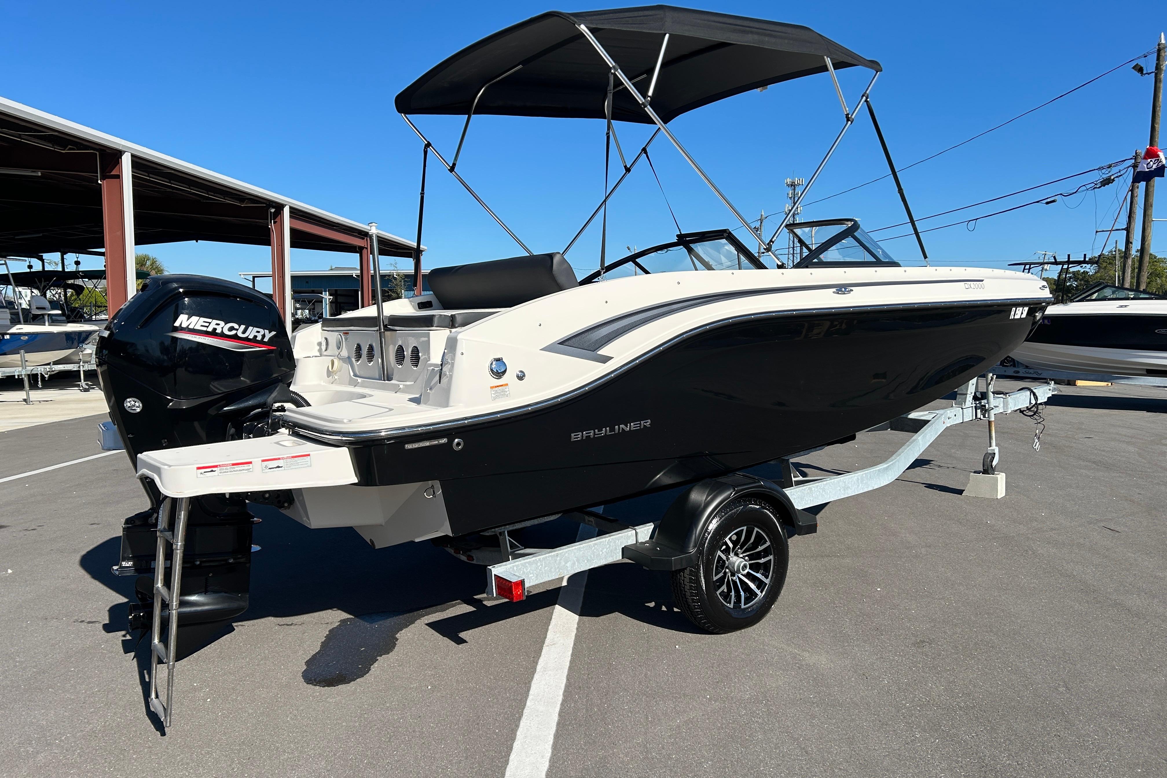 2020 Bayliner DX 2000 boat with Mercury engine on trailer, parked outdoors.