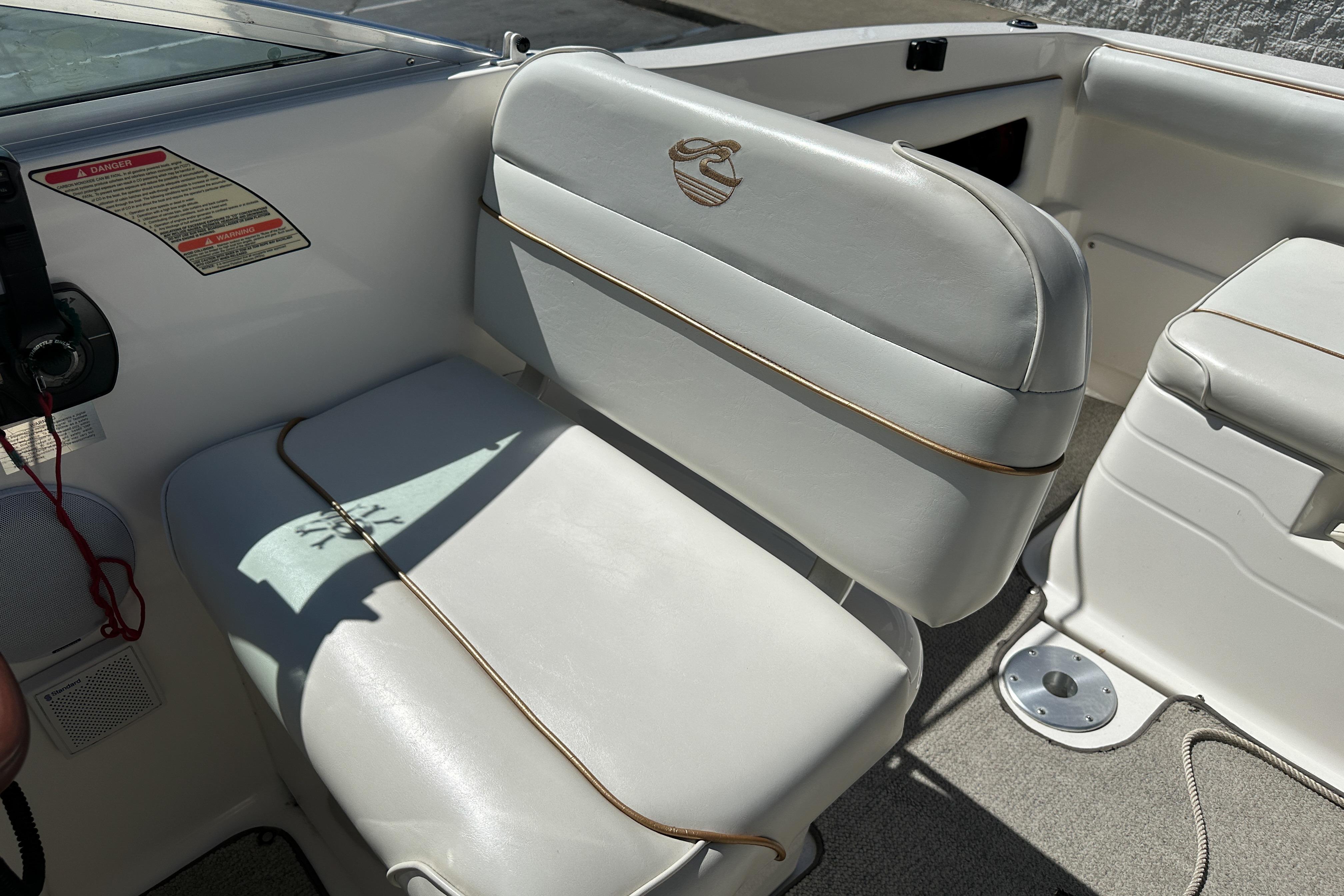 1998 Sea Ray 215 Express Cruiser interior with white seating and control panel.