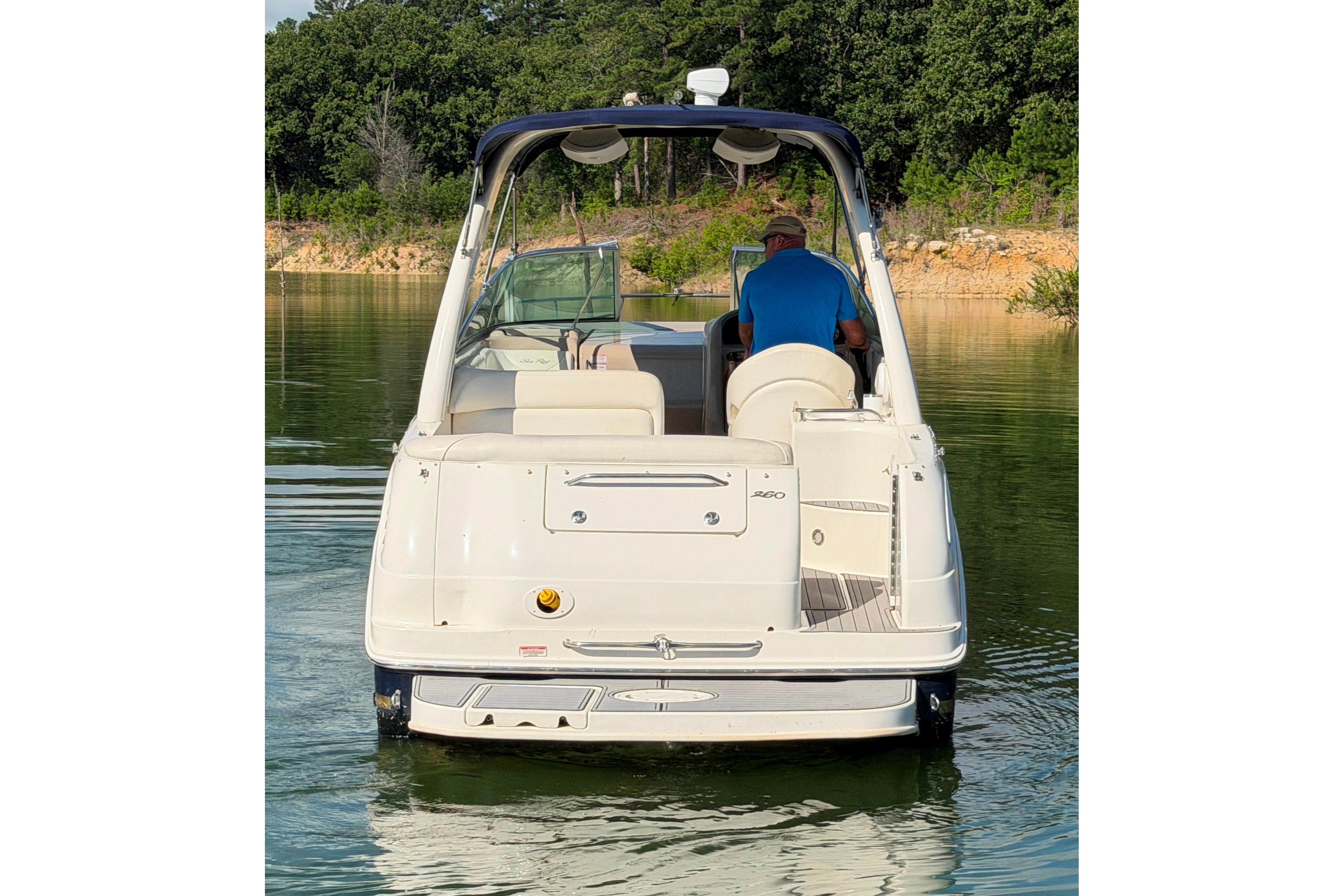 2004 Sea Ray Sundancer 260 boat on calm water, rear view with lush greenery.