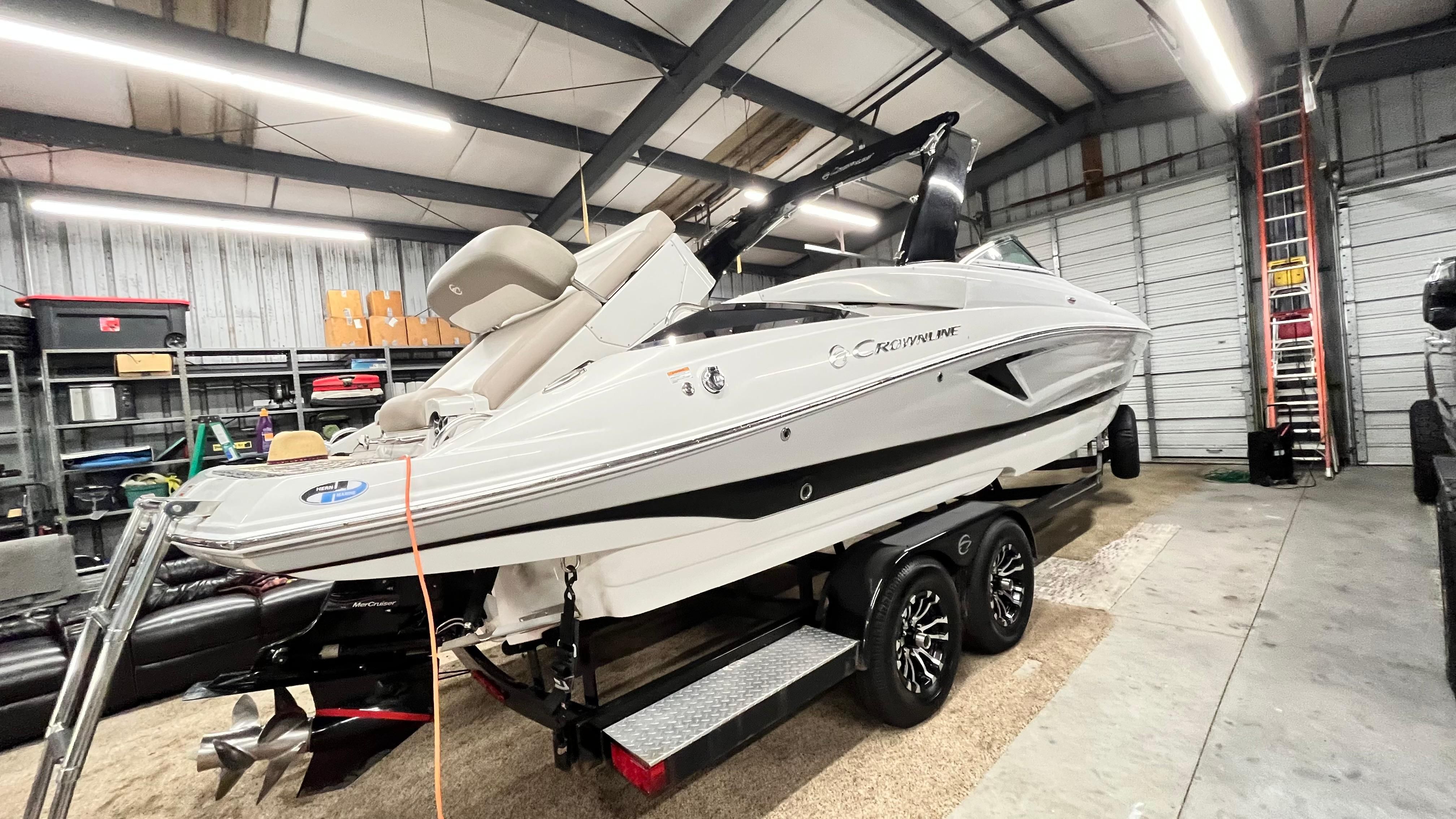 A 2019 Crownline E 285 is on a trailer in a storage facility.