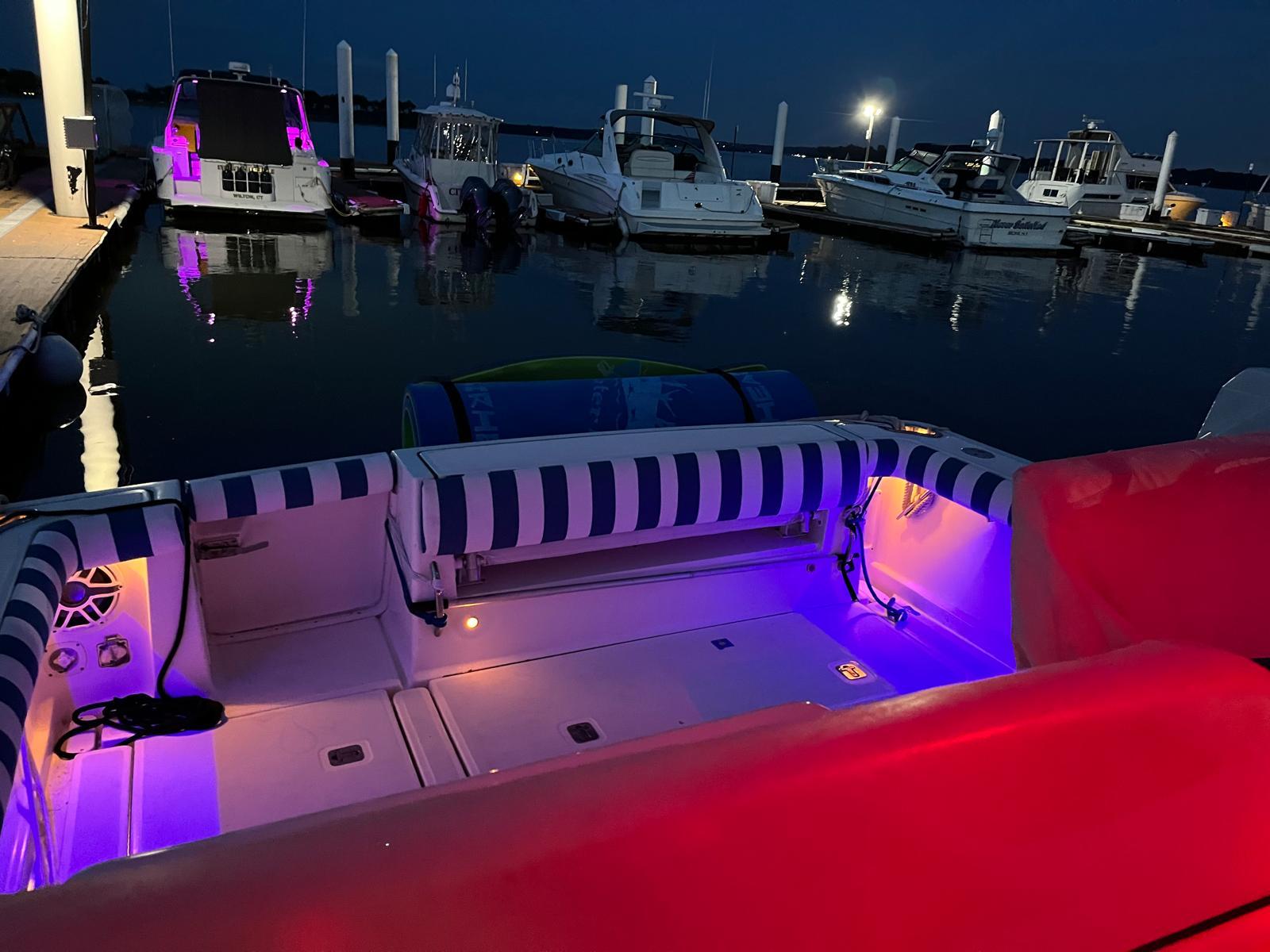 2006 Tiara Yachts 3200 Open with colorful deck lights at night in marina.