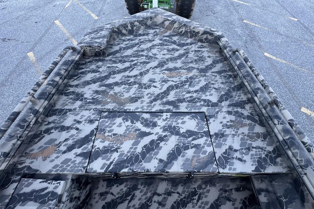 Camouflage-patterned deck of a 2025 Havoc 1860 boat, parked on asphalt.