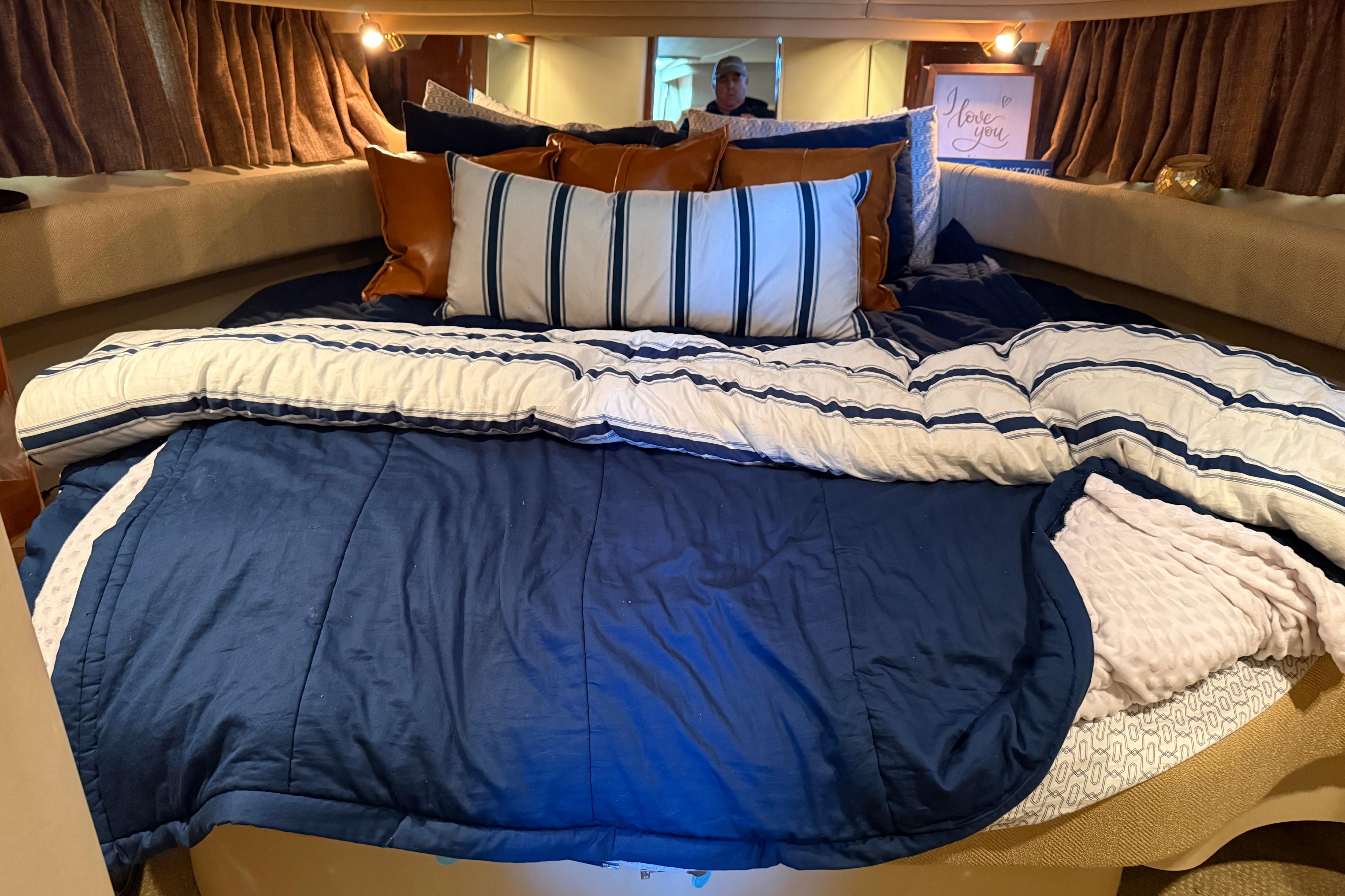 Cozy cabin interior of 2001 Sea Ray 380 Sundancer with plush bedding and pillows.