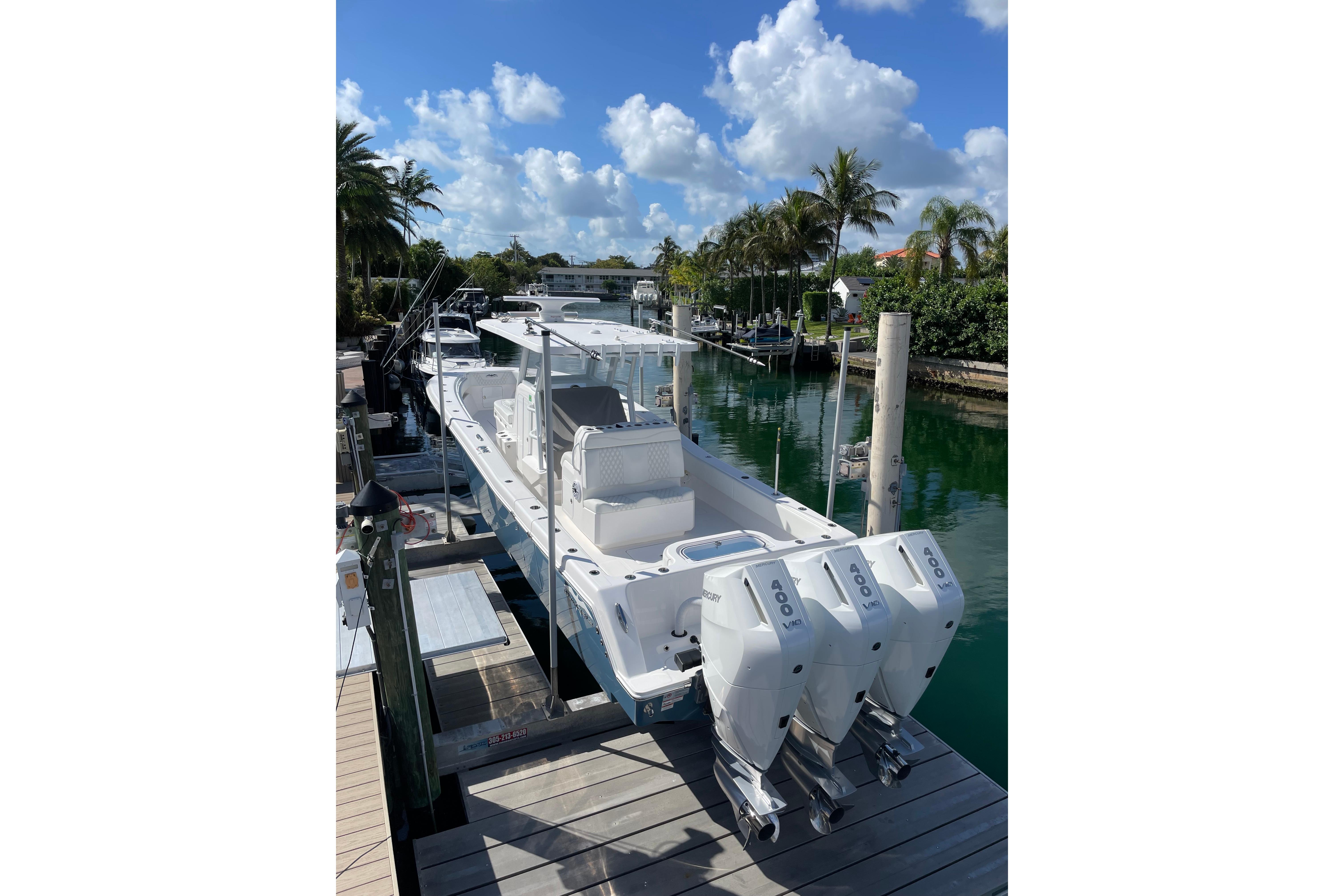 2024 Invincible 36 Open Fisherman boat docked, featuring triple outboard engines, under a clear blue sky.