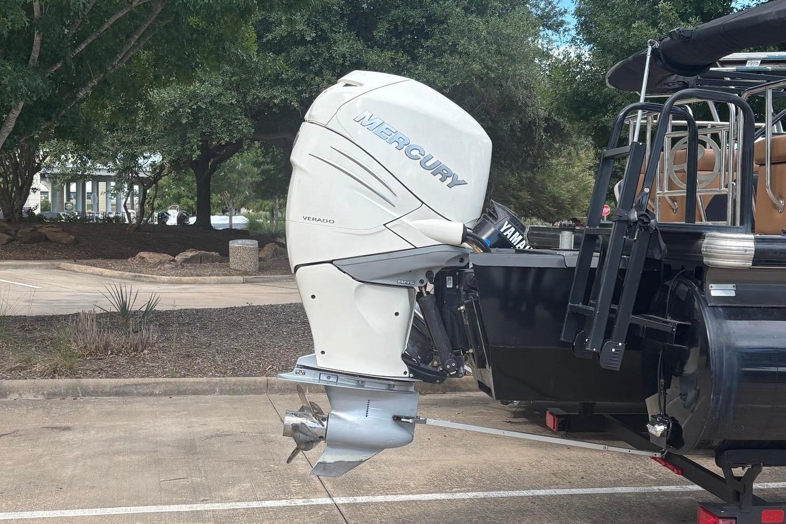 A Mercury boat engine on a trailer, surrounded by trees.