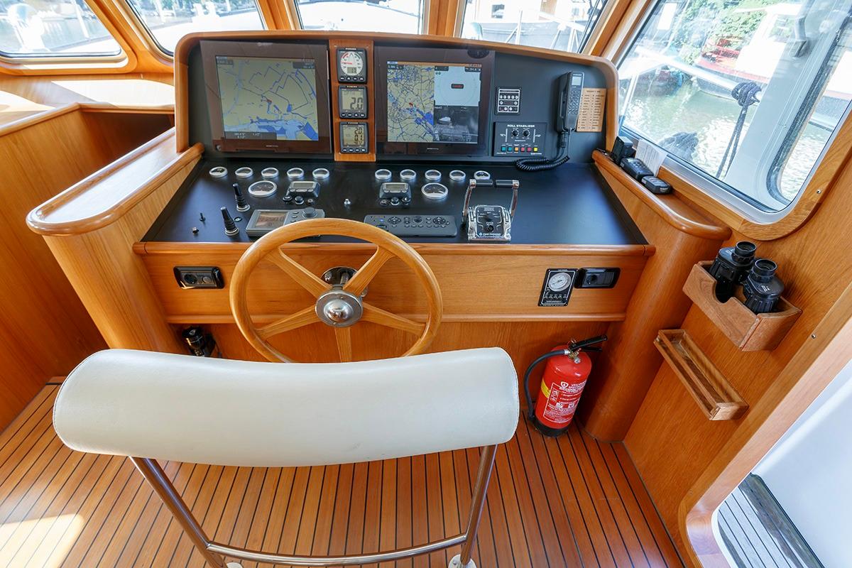 Pilothouse of 2009 Altena 53 Custom Trawler with navigation equipment and wooden steering wheel.