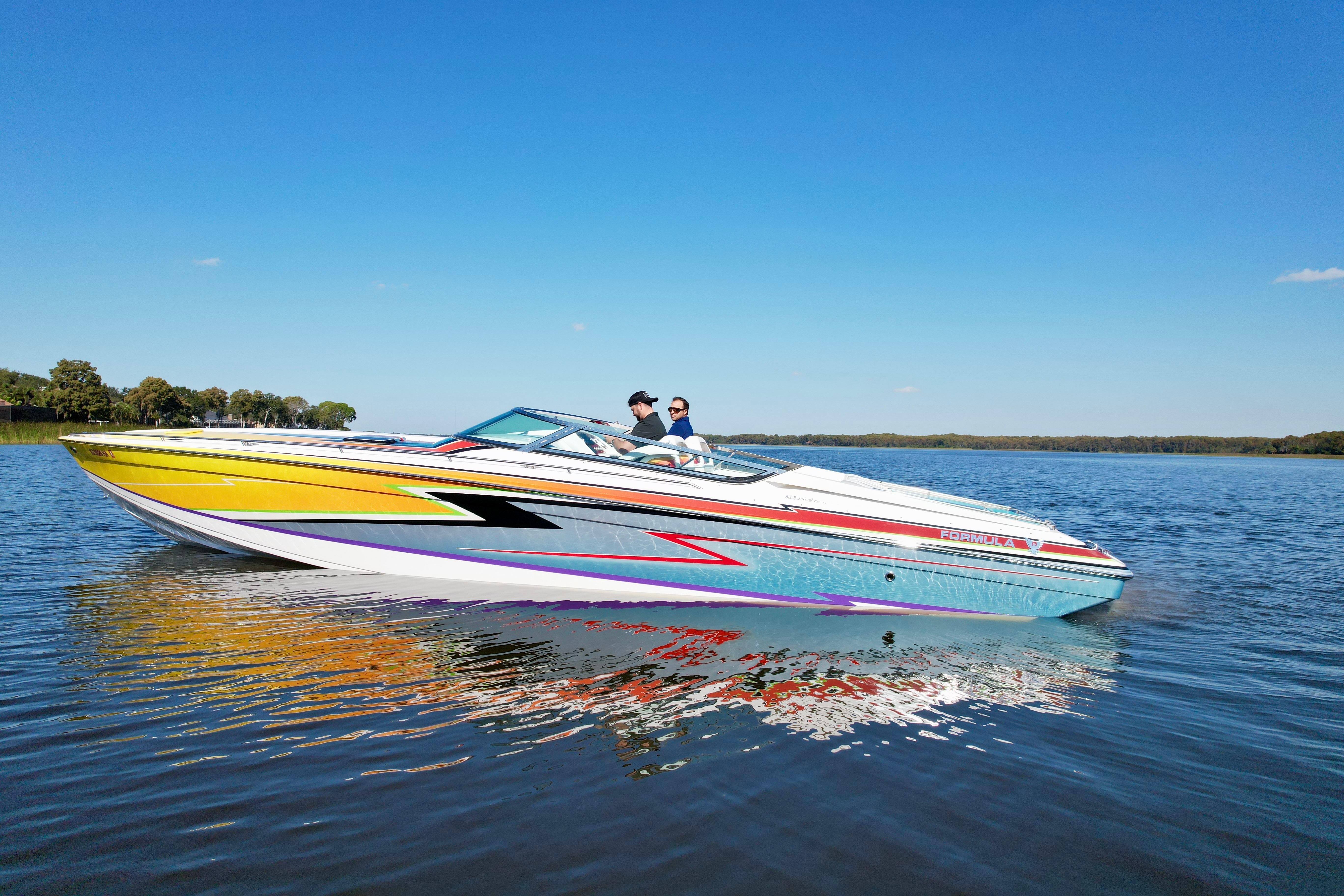 2006 Formula 382 FASTech speedboat cruising on a calm lake under a clear blue sky.