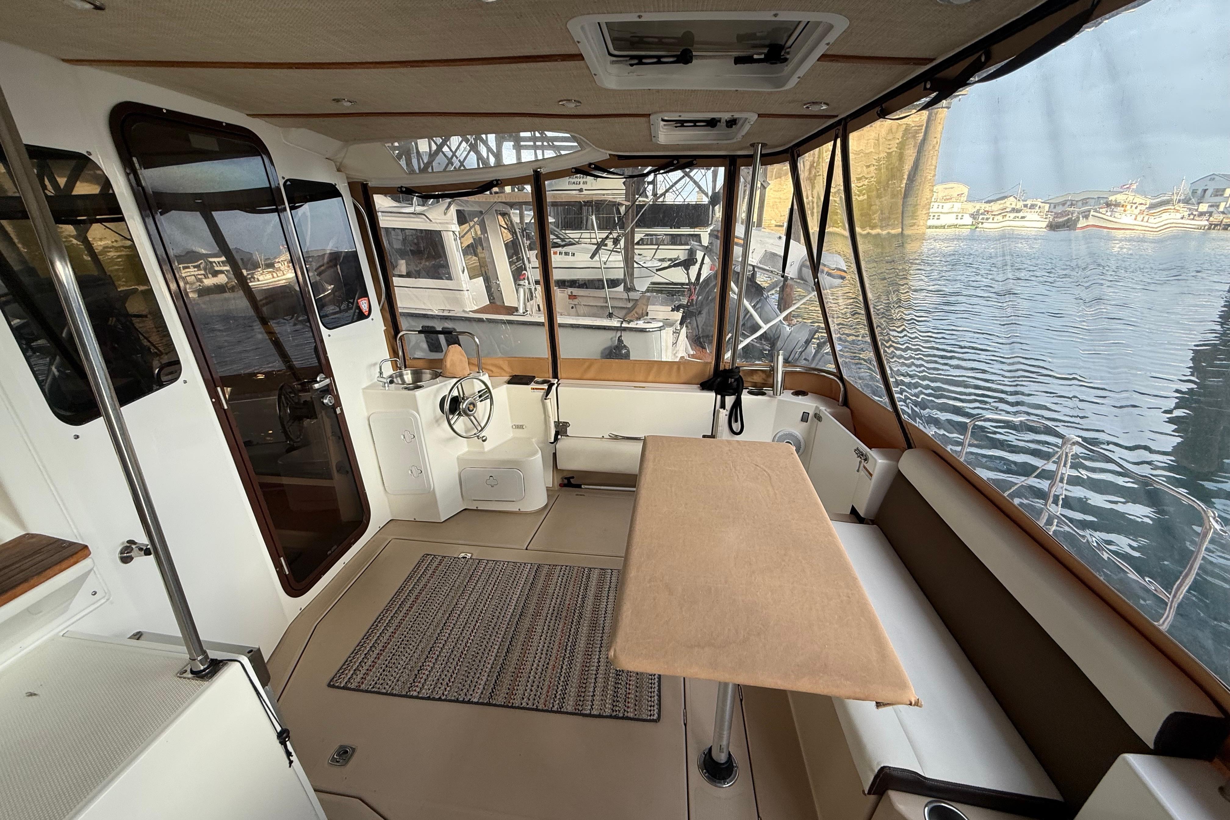 2016 Ranger Tugs R-31 CB interior with helm, seating, and marina view.