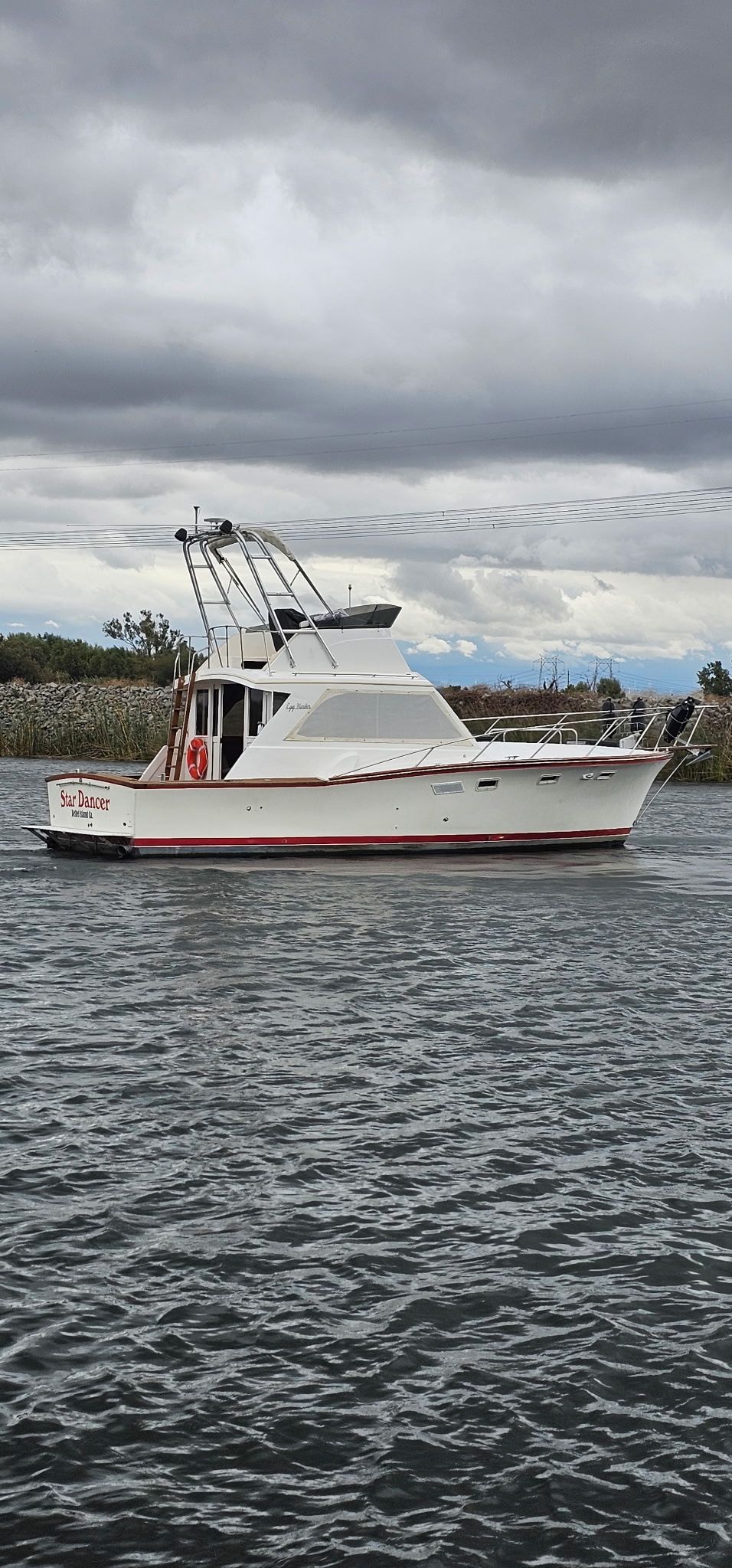 Egg Harbor 33 Sportfisher 1976 on calm water under cloudy sky.