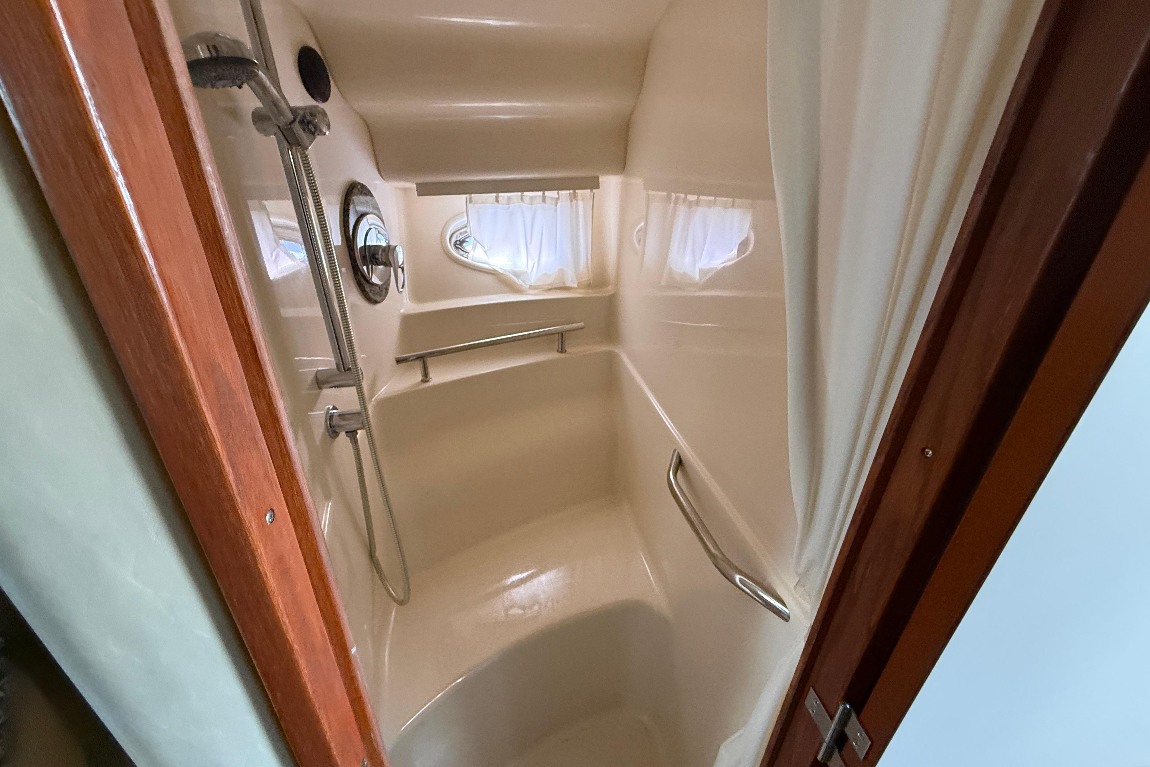 Shower area in 2005 Sea Ray 390 Sundancer yacht with curtain and porthole window.