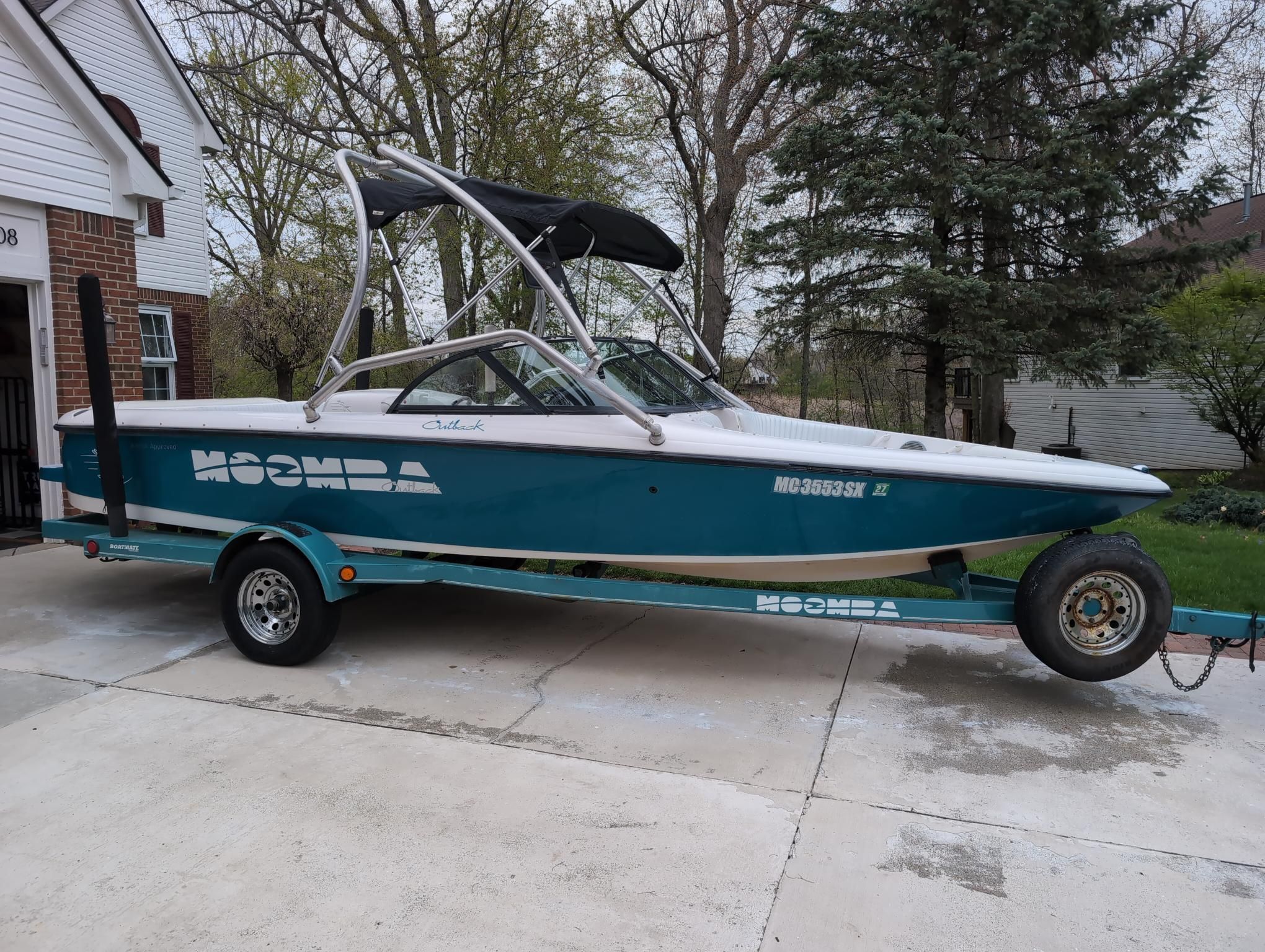 A 2000 Moomba Ouback LS boat on a trailer in a driveway.