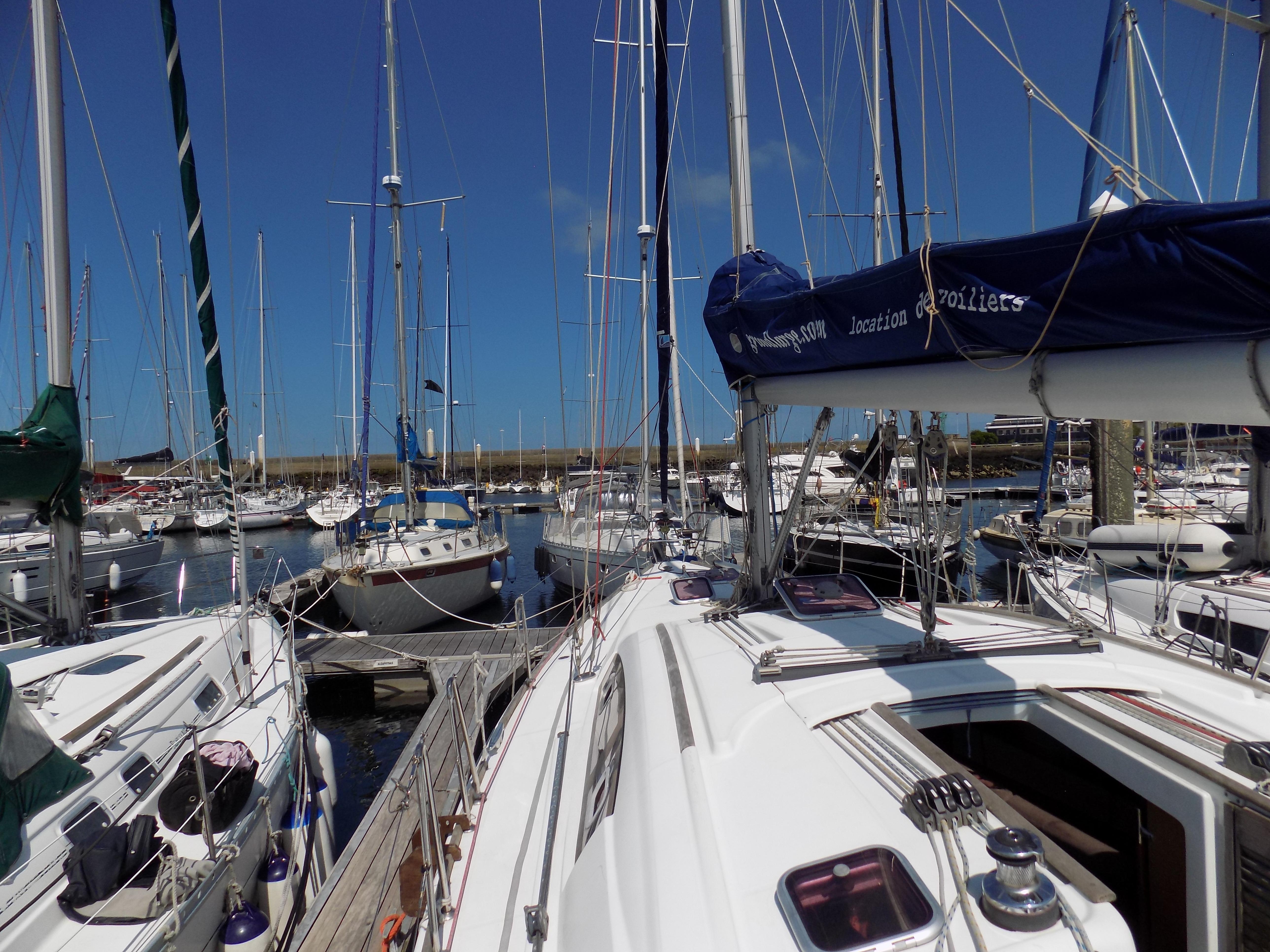 Beneteau Oceanis 43 sailboat docked in a marina, surrounded by other boats, under clear blue skies.