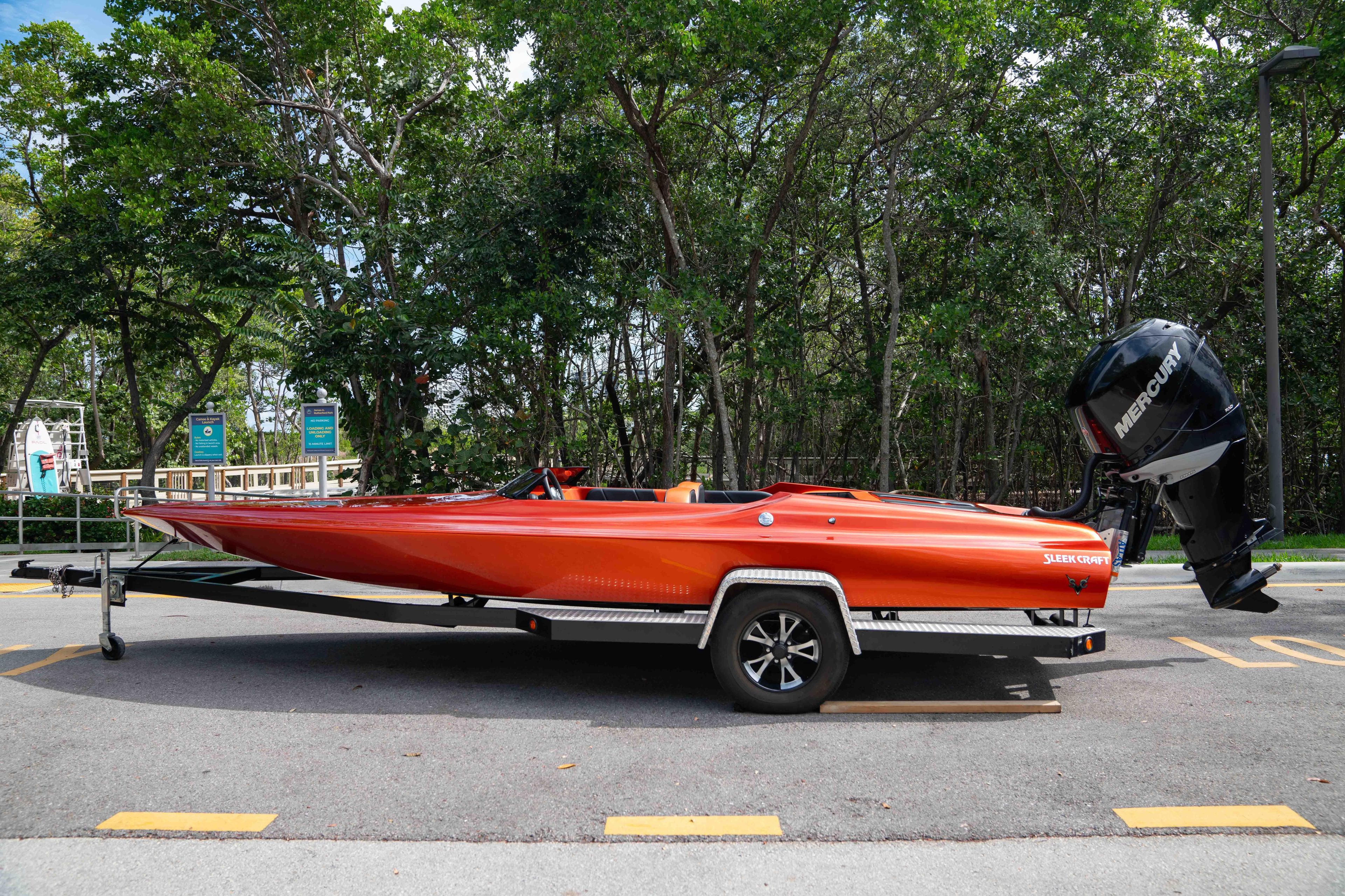 1984 Sleekcraft Aristocrat 20 boat on trailer, vibrant orange, parked outdoors.