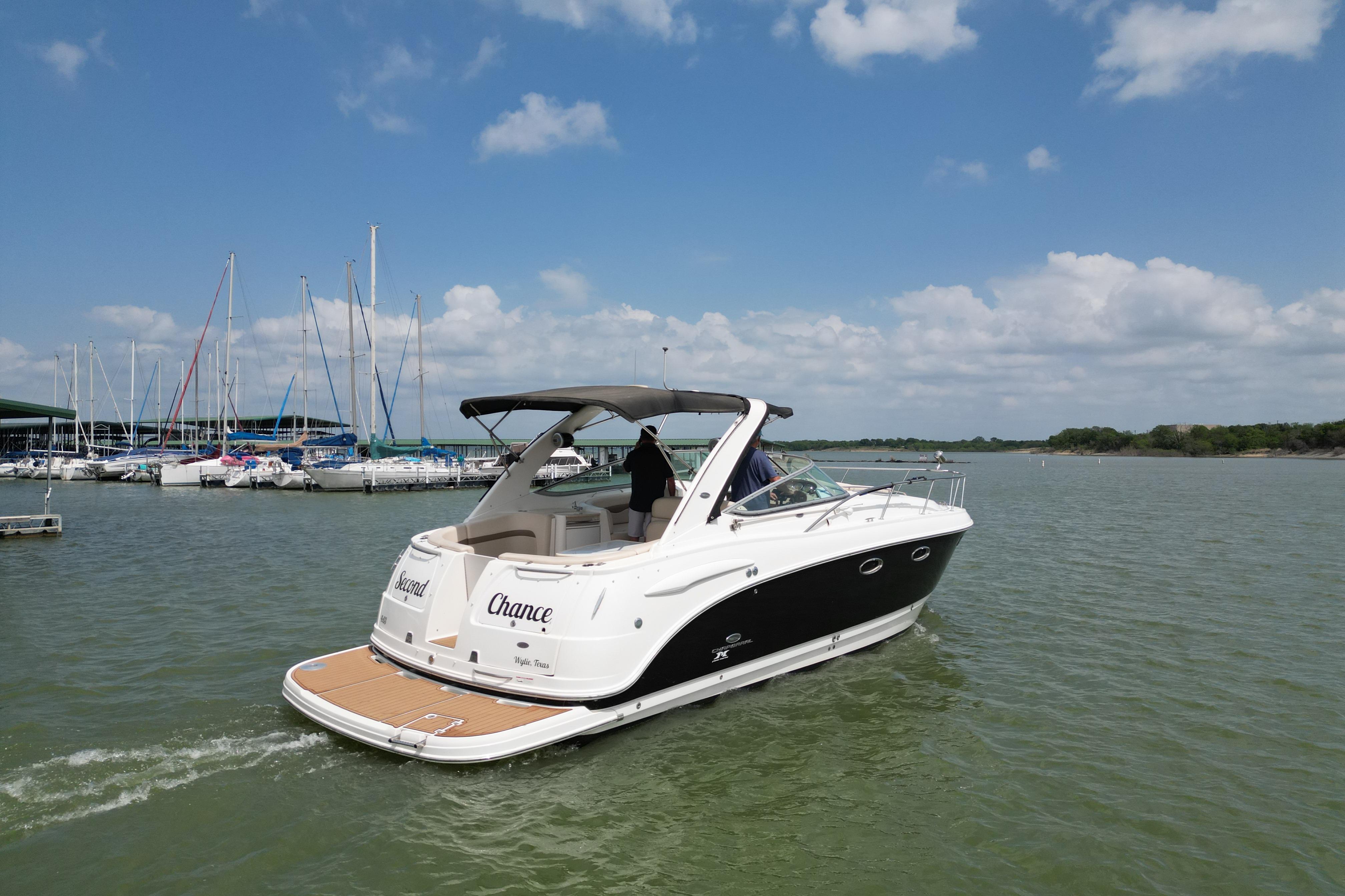 2006 Chaparral 330 Signature boat cruising on a lake under a clear blue sky.
