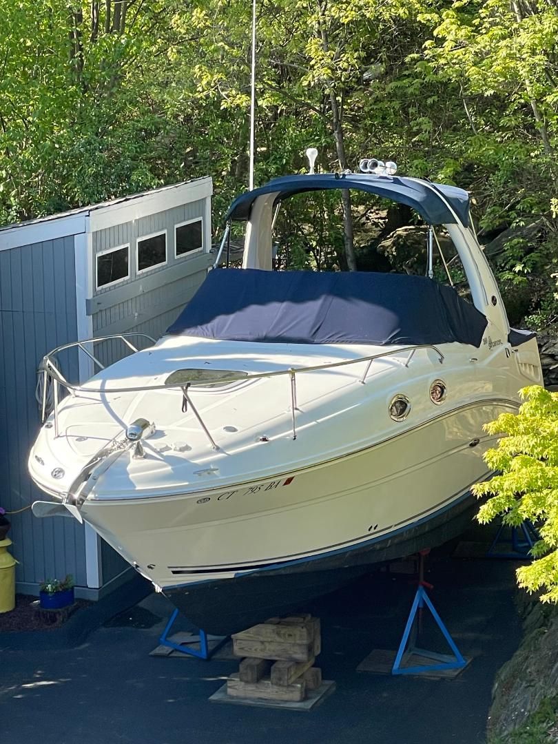A 2005 Sea Ray Sundancer 260 is on a stand next to a building.