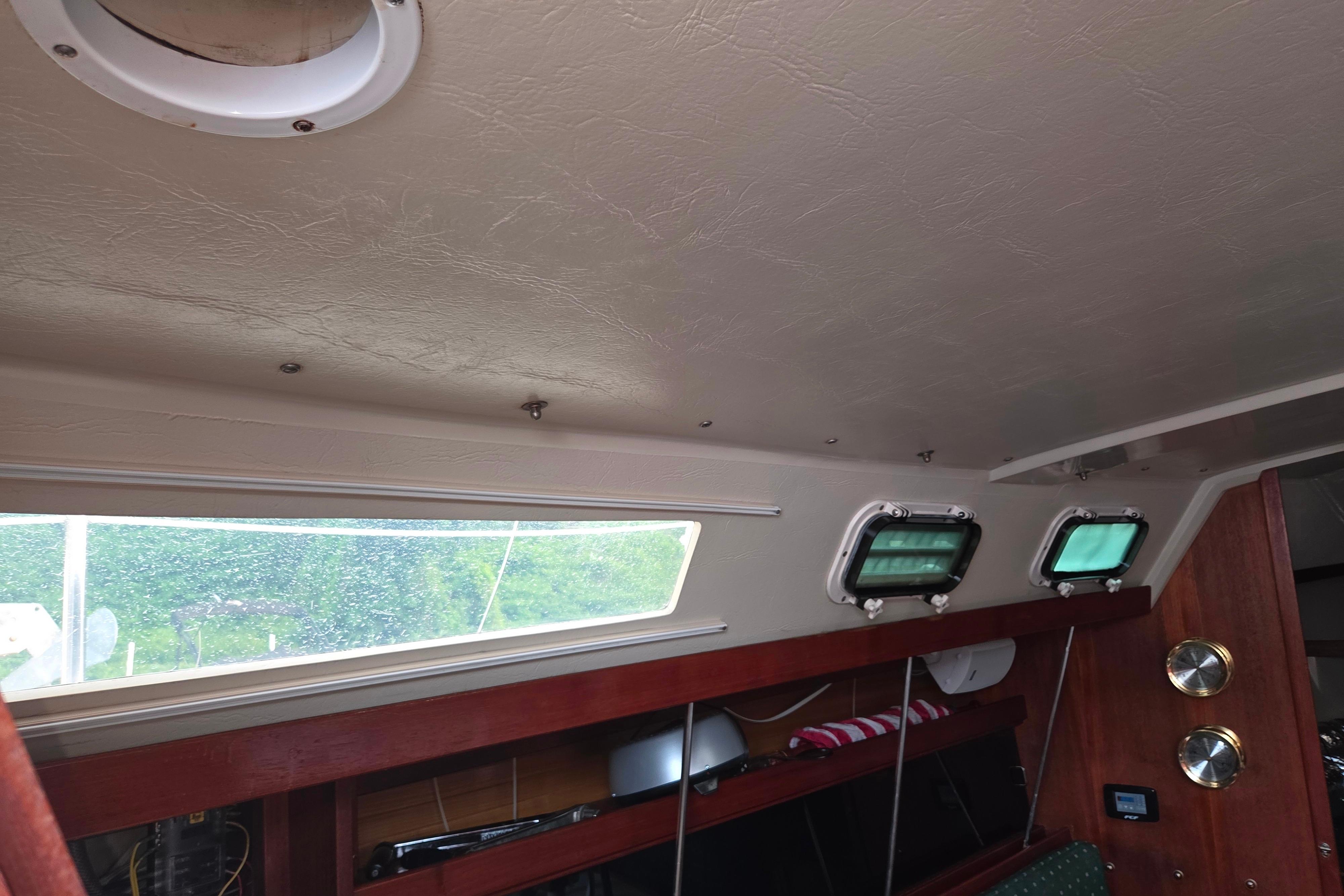 Interior of a 1986 Catalina 355 sailboat with portholes and wooden accents.