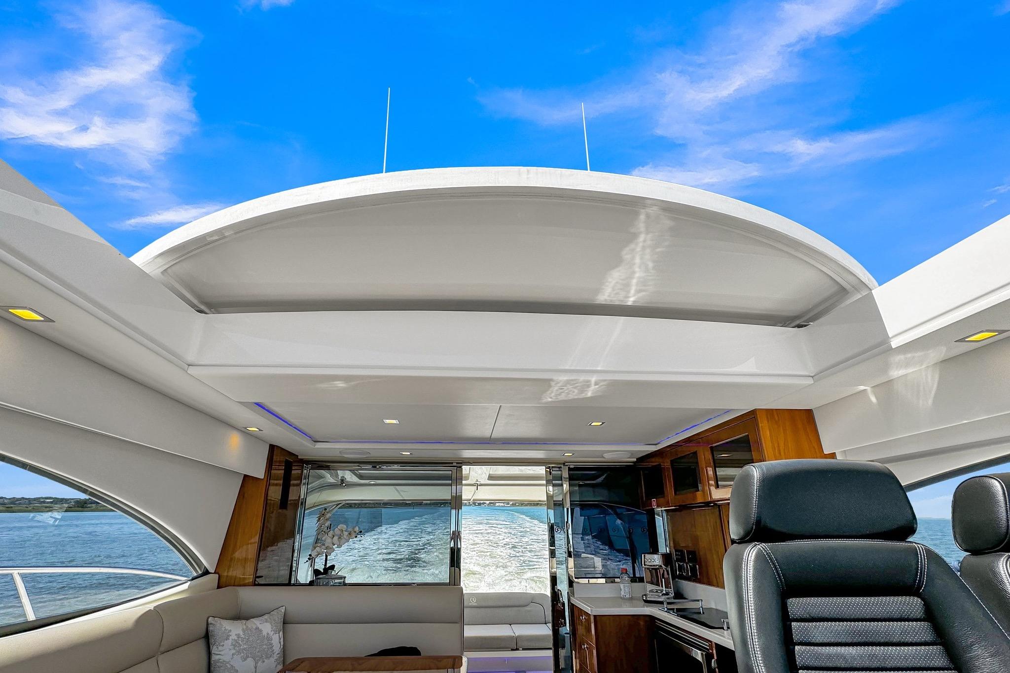 Interior view of 2020 Riviera 4800 Sport Yacht with open roof and ocean backdrop.
