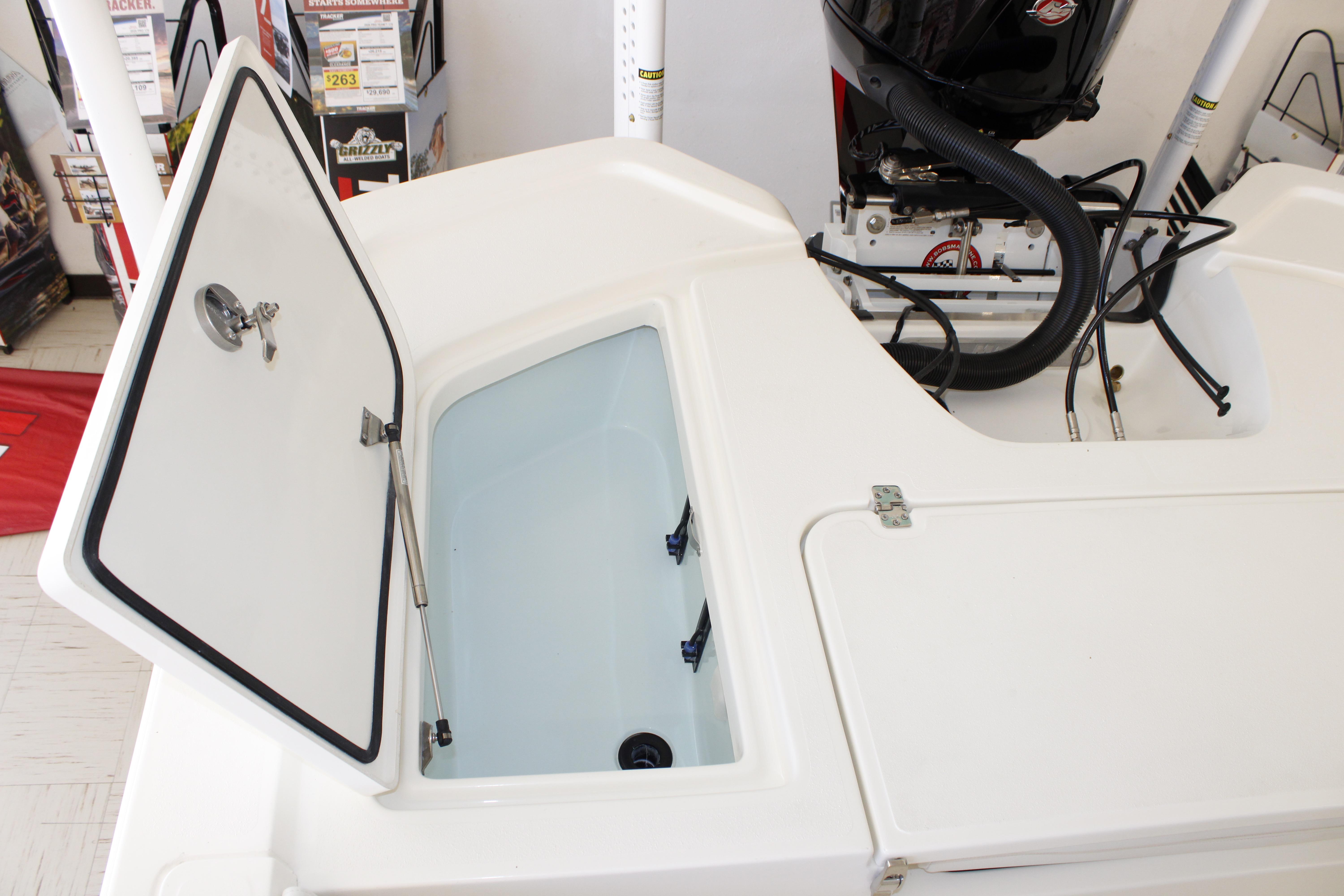 Open storage compartment on 2026 Mako 24 APEX boat, showcasing interior and engine components.