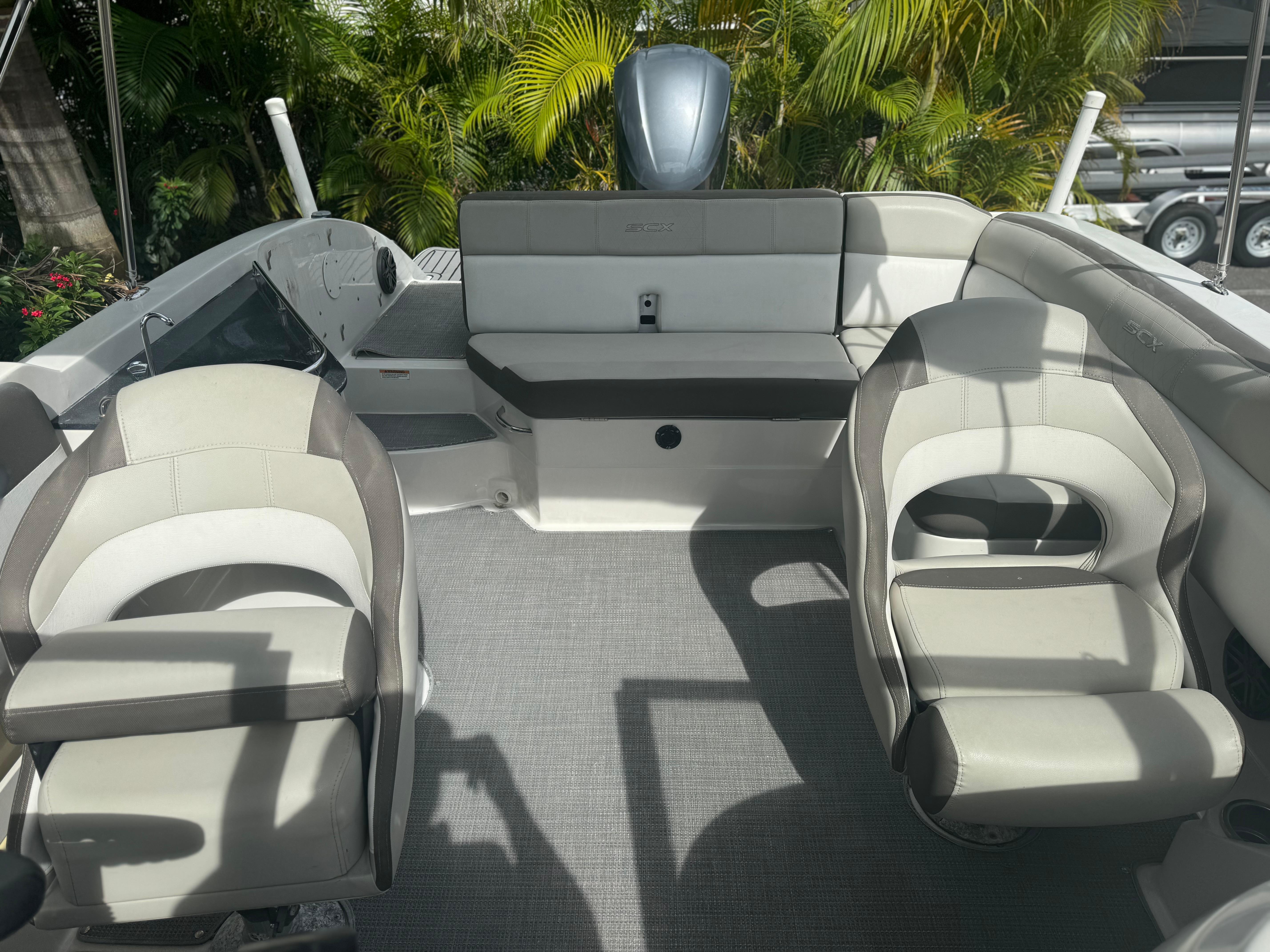2017 Starcraft 230 OB SCX EXT boat interior with seating and helm, surrounded by lush greenery.