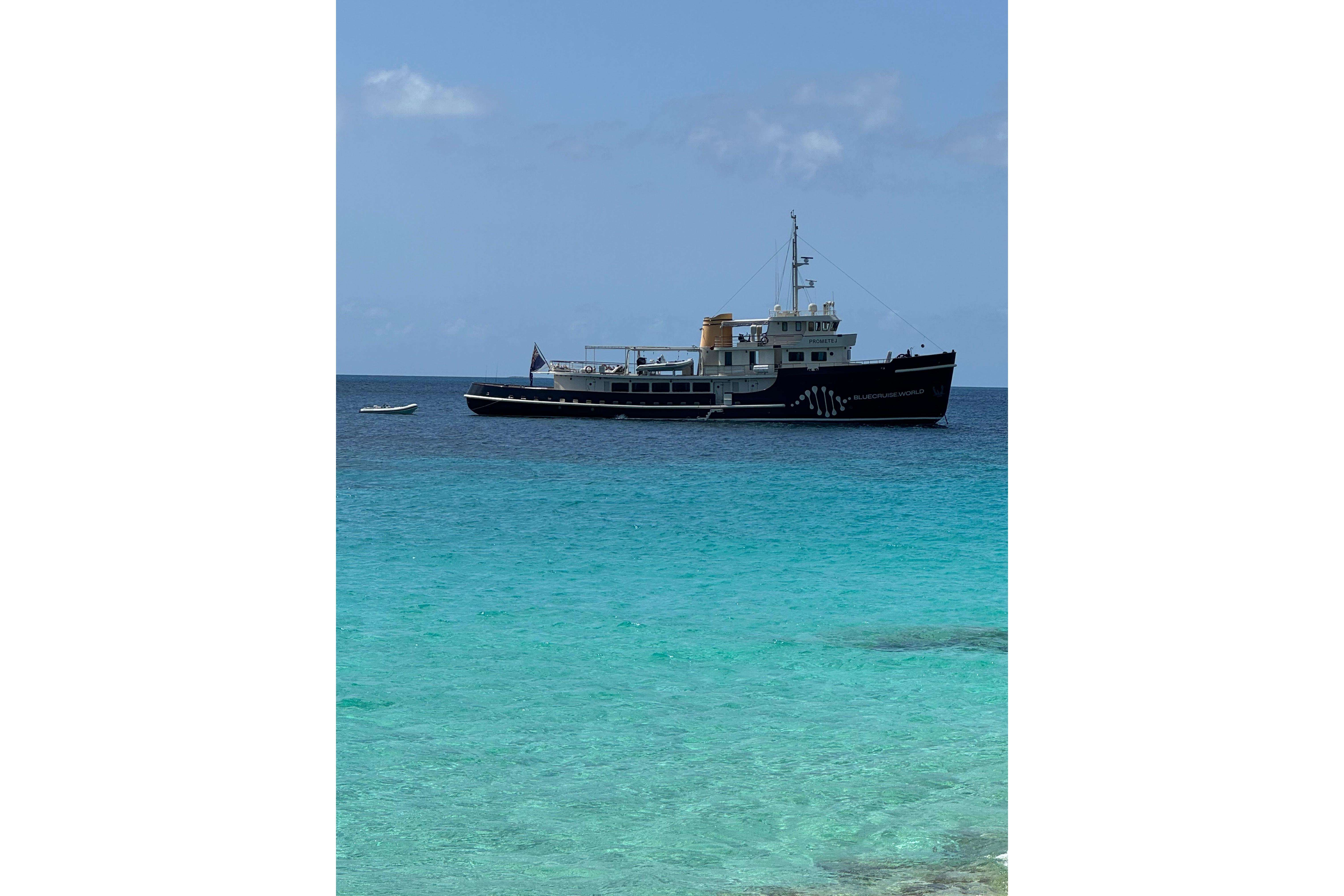 Custom 1956 converted tugboat anchored in clear turquoise waters under a blue sky.